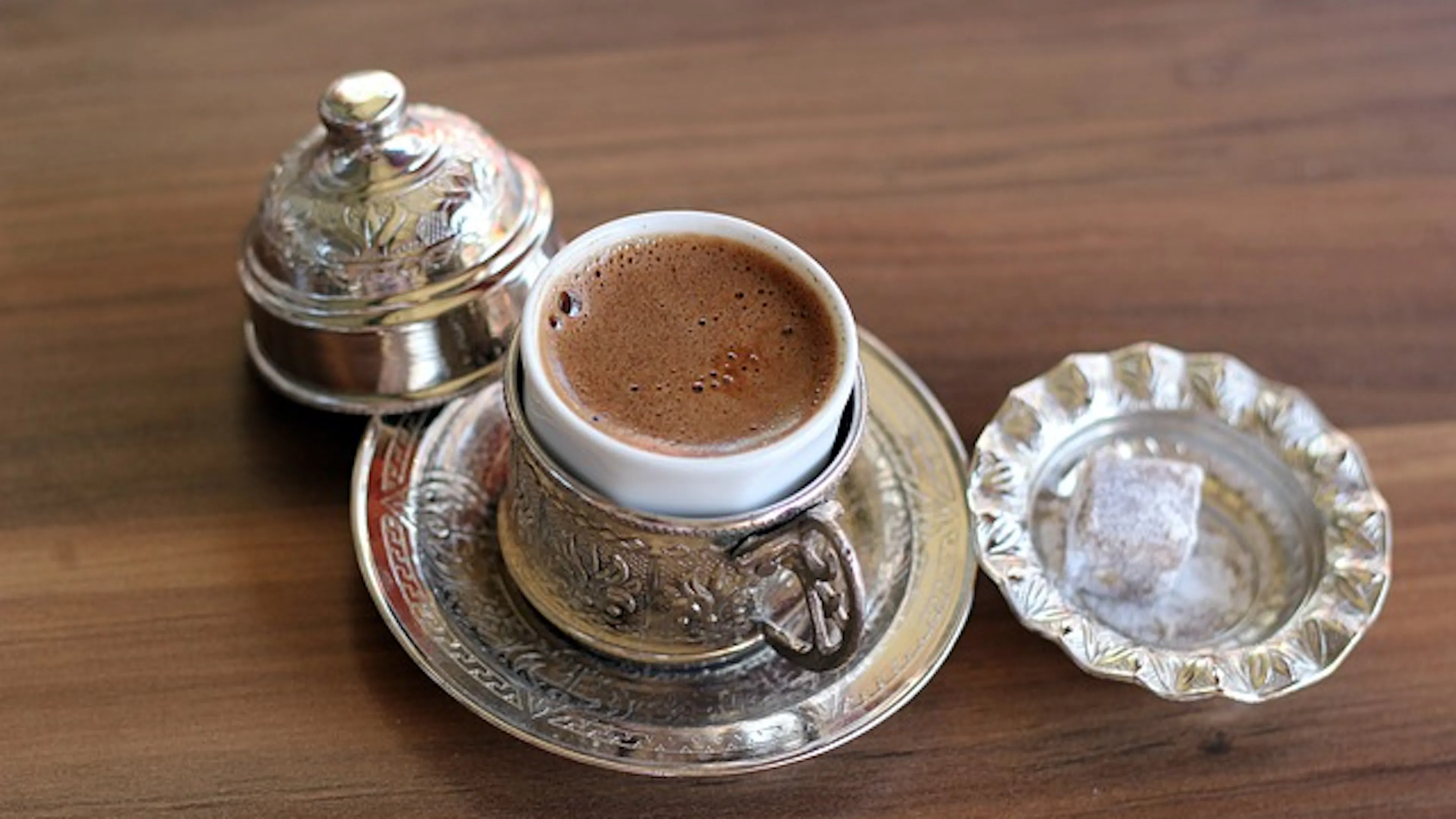 Turkish coffee in a traditional metal cup holder on a wooden table