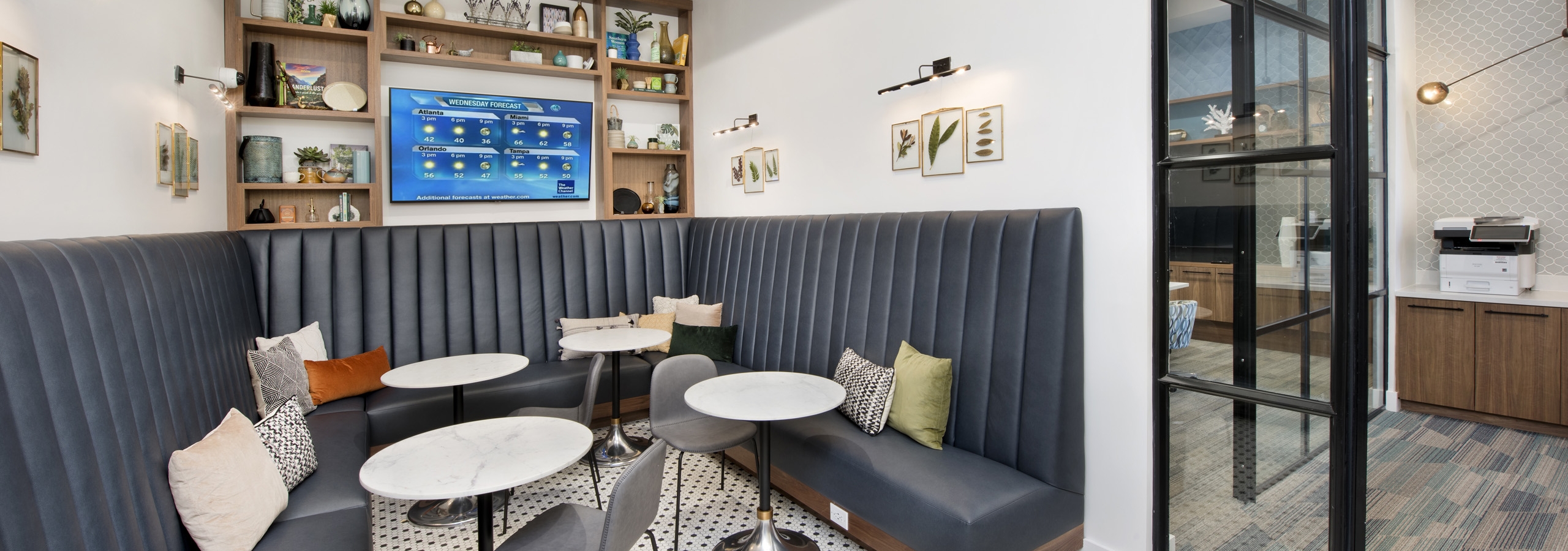 Interior view of tech center at AMLI Decatur with large screen TV and cafe tables and chairs with booth seating