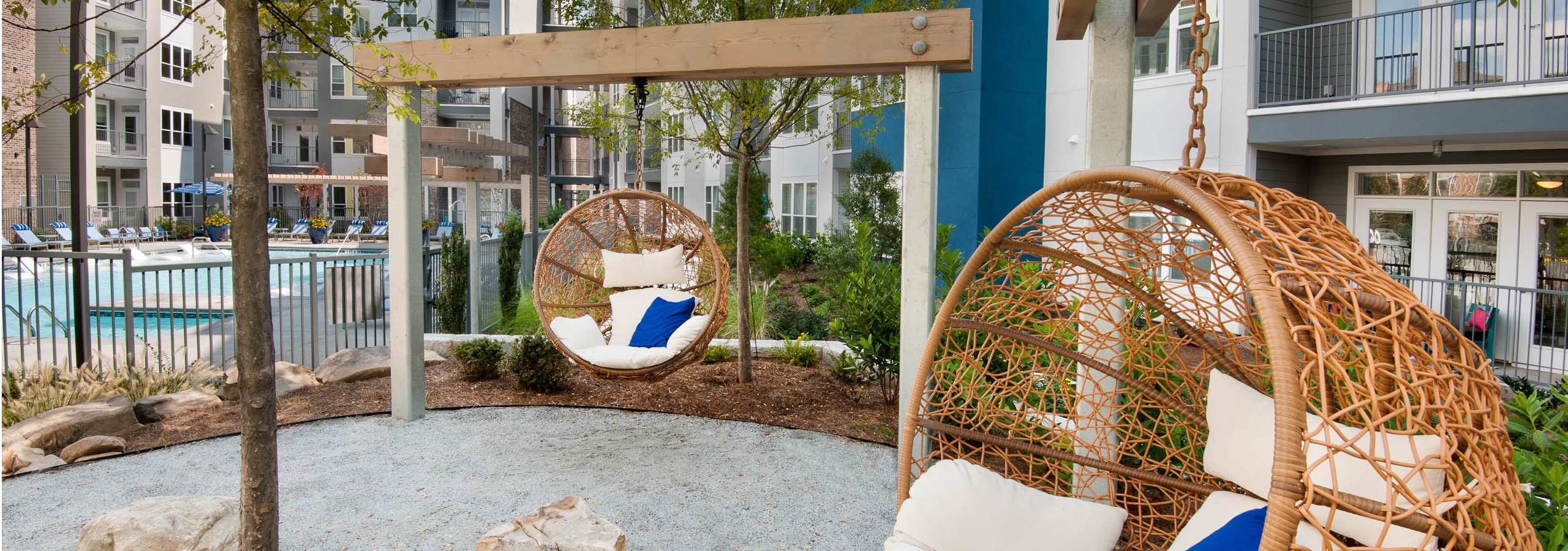 AMLI Piedmont Heights sitting area in courtyard near the pool showing wicker egg shaped swinging chairs with cream cushions