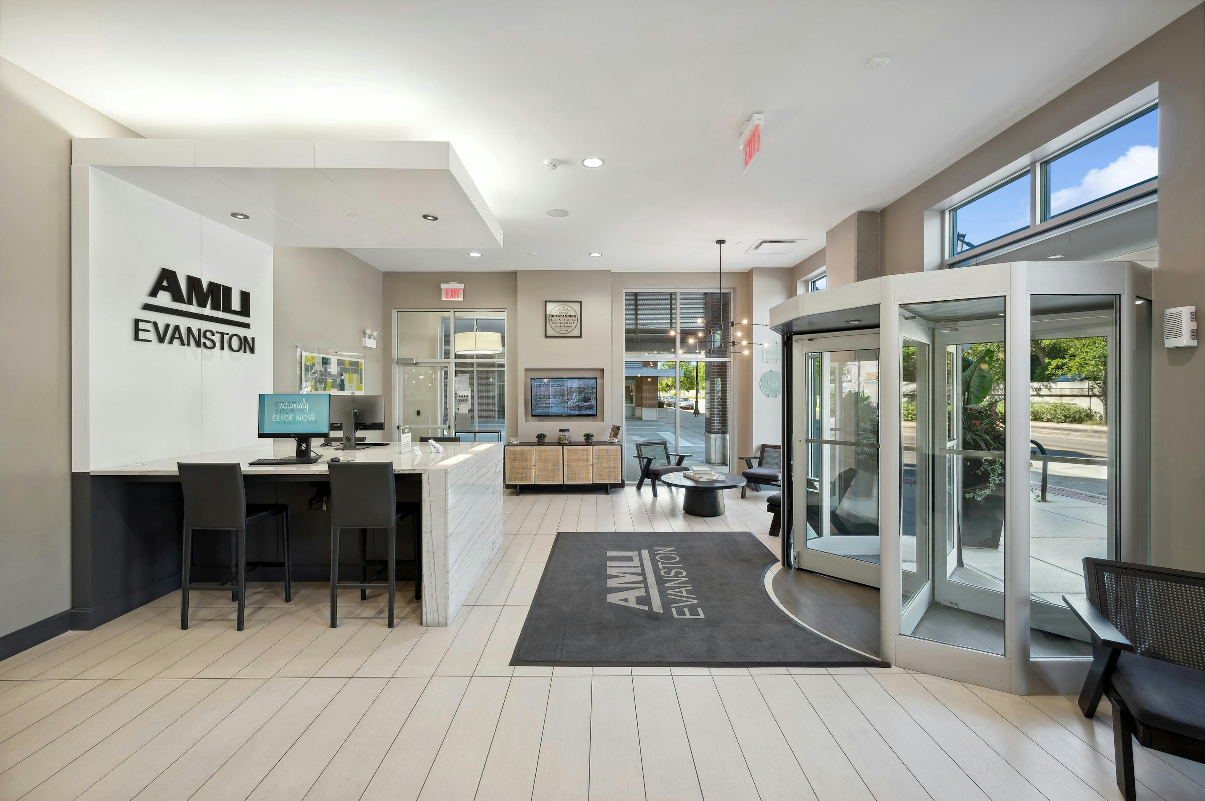 Leasing office at AMLI Evanston with white bar top with computers with logo above facing revolving glass door