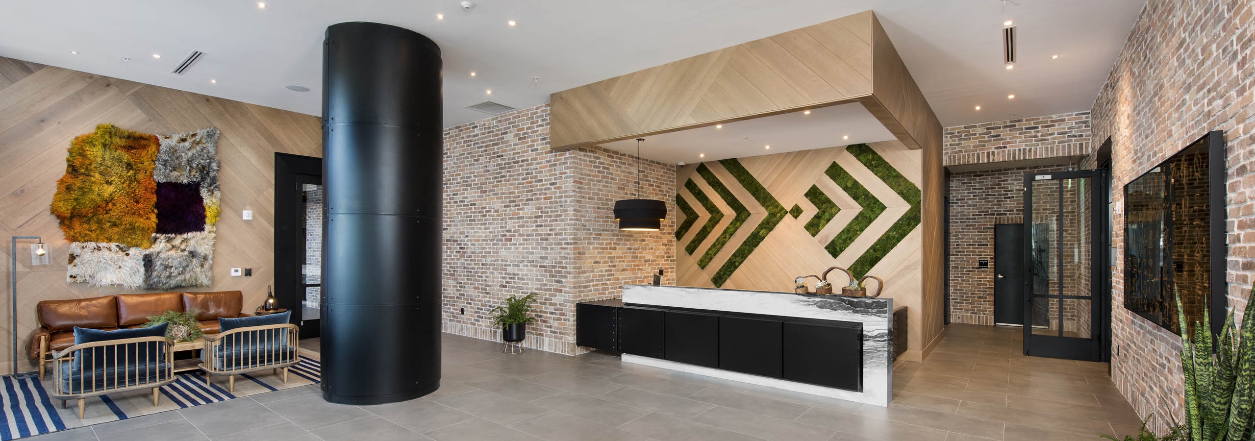 AMLI Midtown 29 lobby with green living and wood wall and brick walls with seating area and large multi-color wall hanging