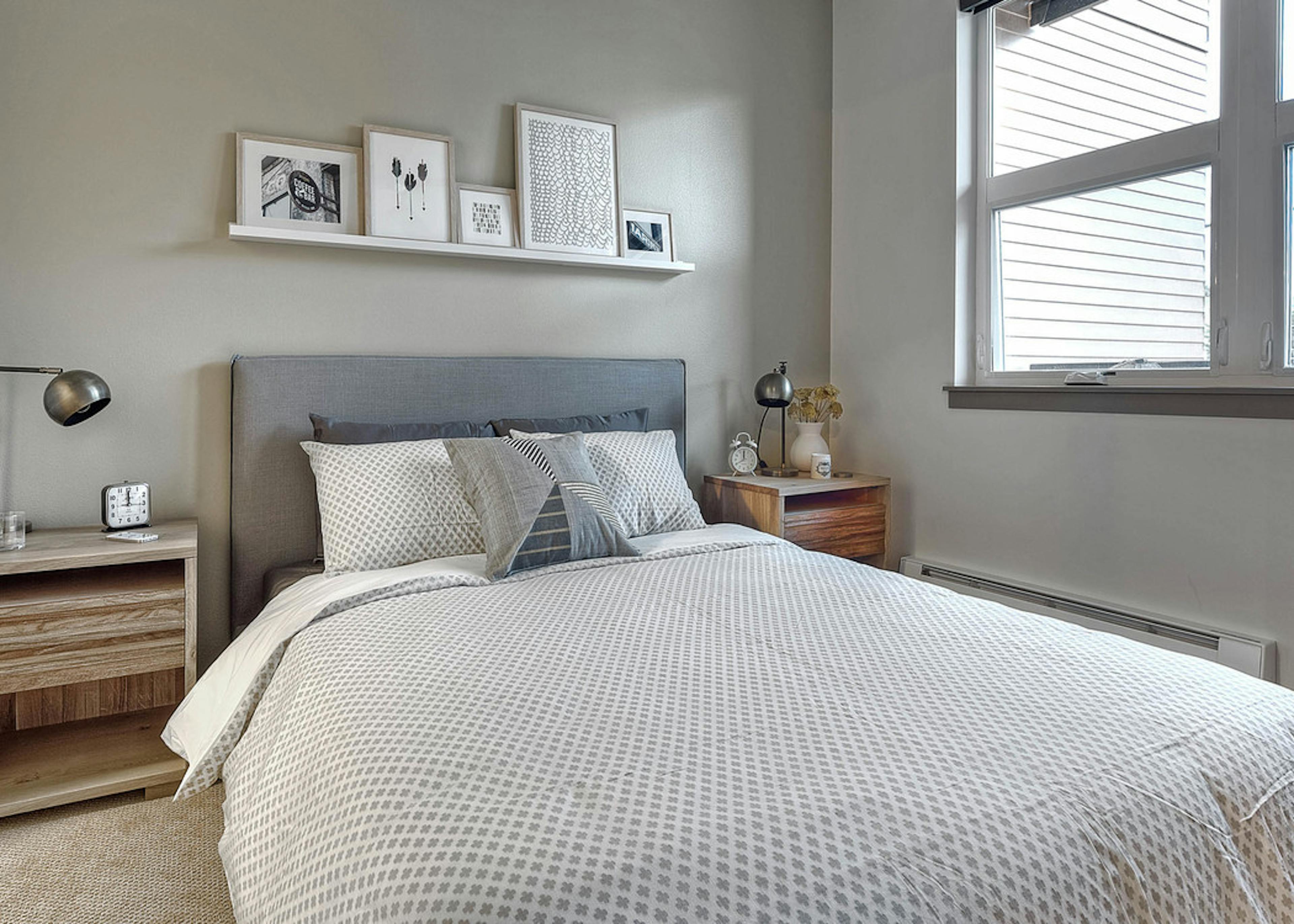 Interior view of AMLI Mark24 bedroom with view of walk-in closet sliding barn door light grey walls and two bedside tables 