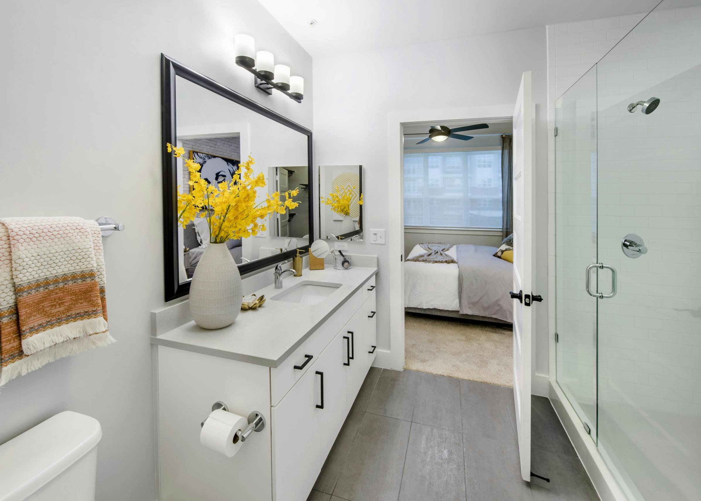 Interior view of AMLI Dectaur apartment bathroom with quartz countertop and framed mirror and frameless glass shower