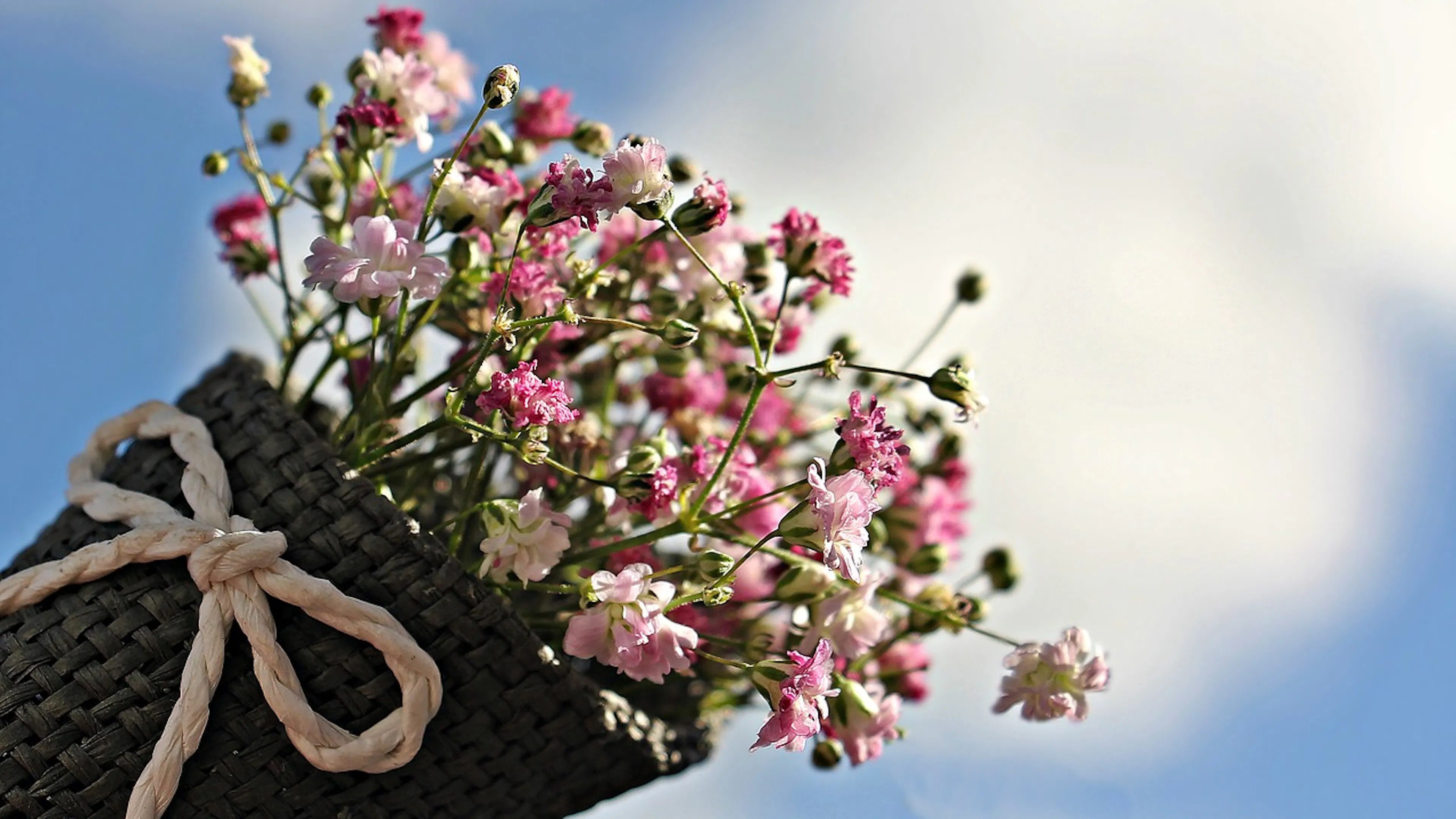 A wicker basket holding a bouquet of dainty pink wildflowers