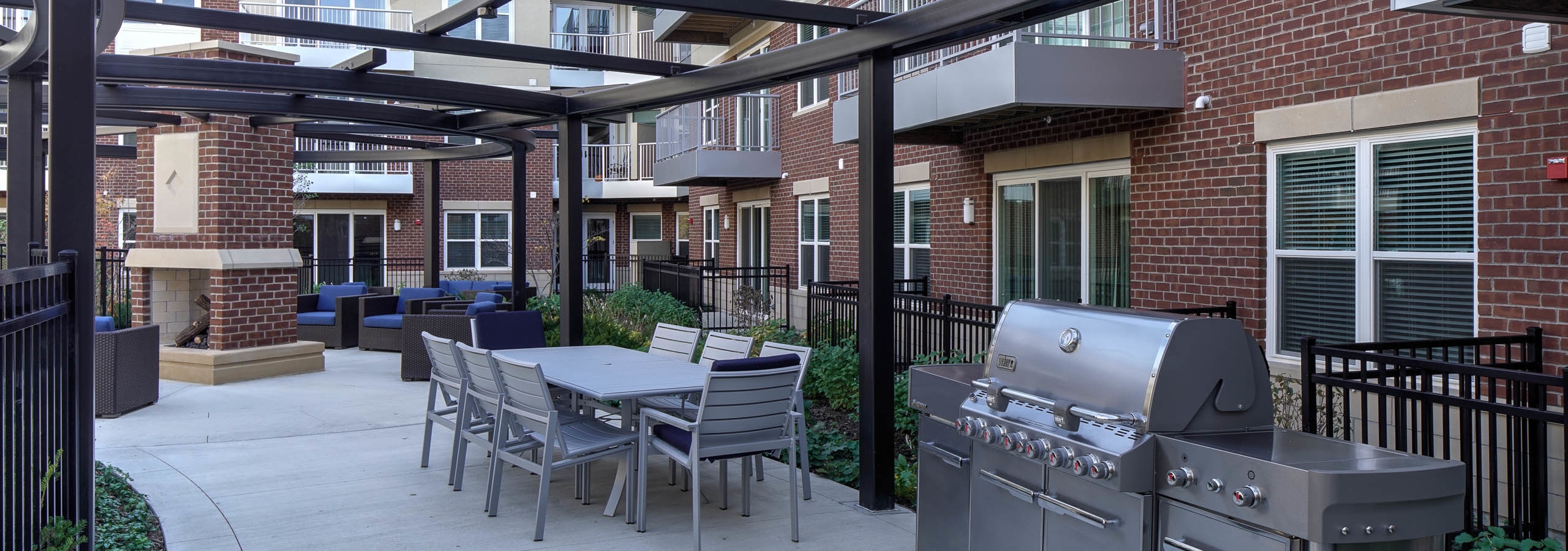 Exterior of courtyard at AMLI Deerfield apartment community with closeup of firepit and pool in background with pool chairs