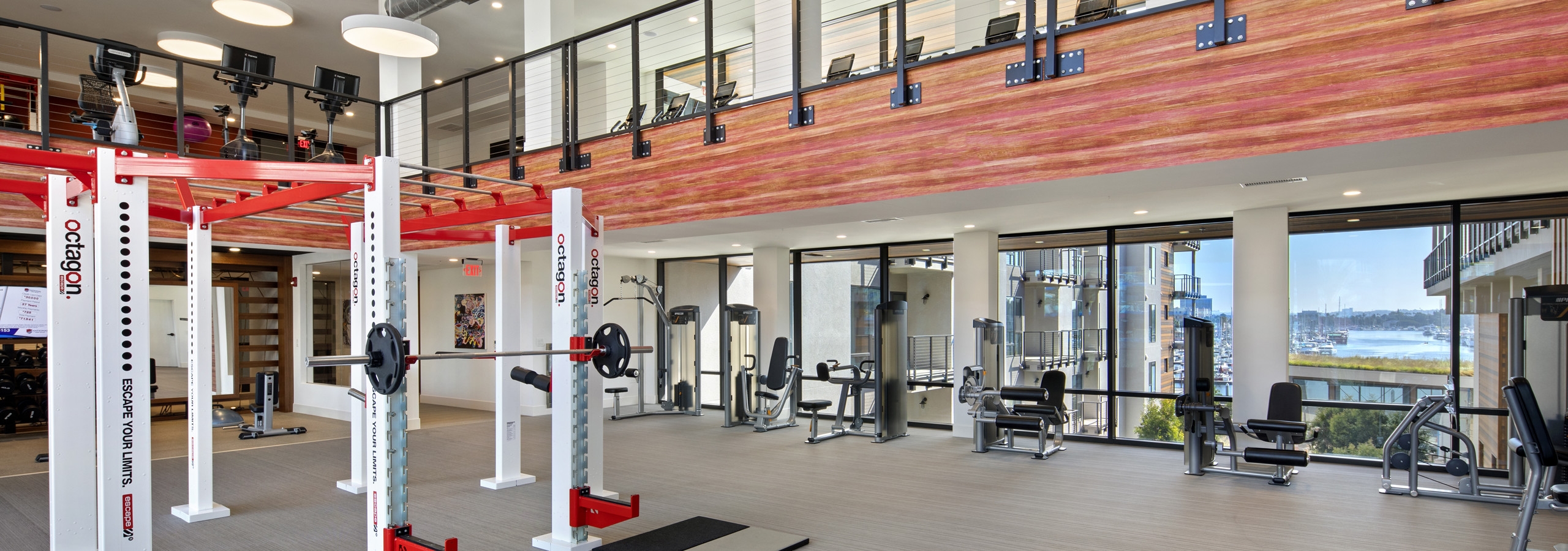 Interior of AMLI Marina Del Rey apartment fitness center with strength workout equipment and motion cage facing the marina