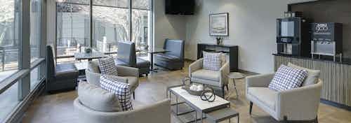 Daytime view of AMLI 900 business center with a java bar and booth and other seating and a big screen TV by 2 walls of windows