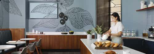 AMLI Fountain Place resident lounge with white serving counters on brown cabinets and tables and chairs and blue wallpaper