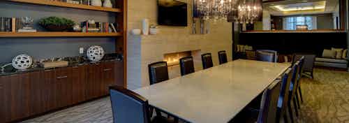 Library at AMLI River North with a long table and black leather chairs and a wooden shelf in the back beside a flat screen TV
