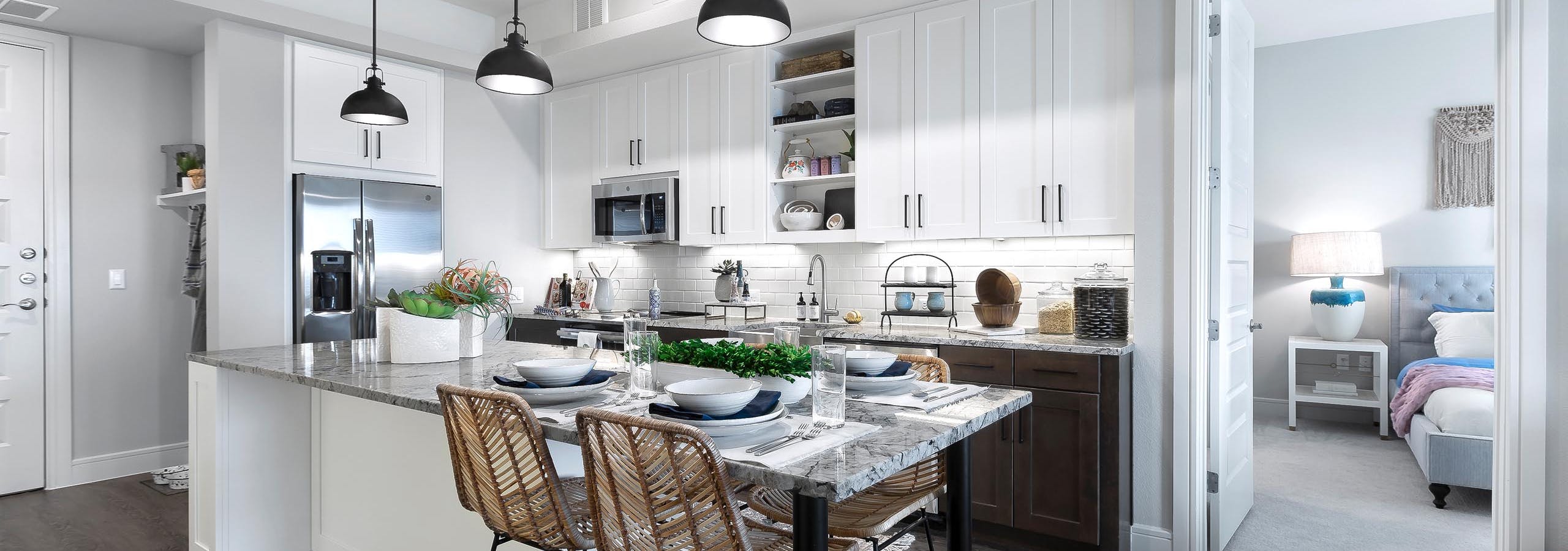 AMLI Lakeline apartment kitchen with stainless steel appliances and dining island with gray granite countertops