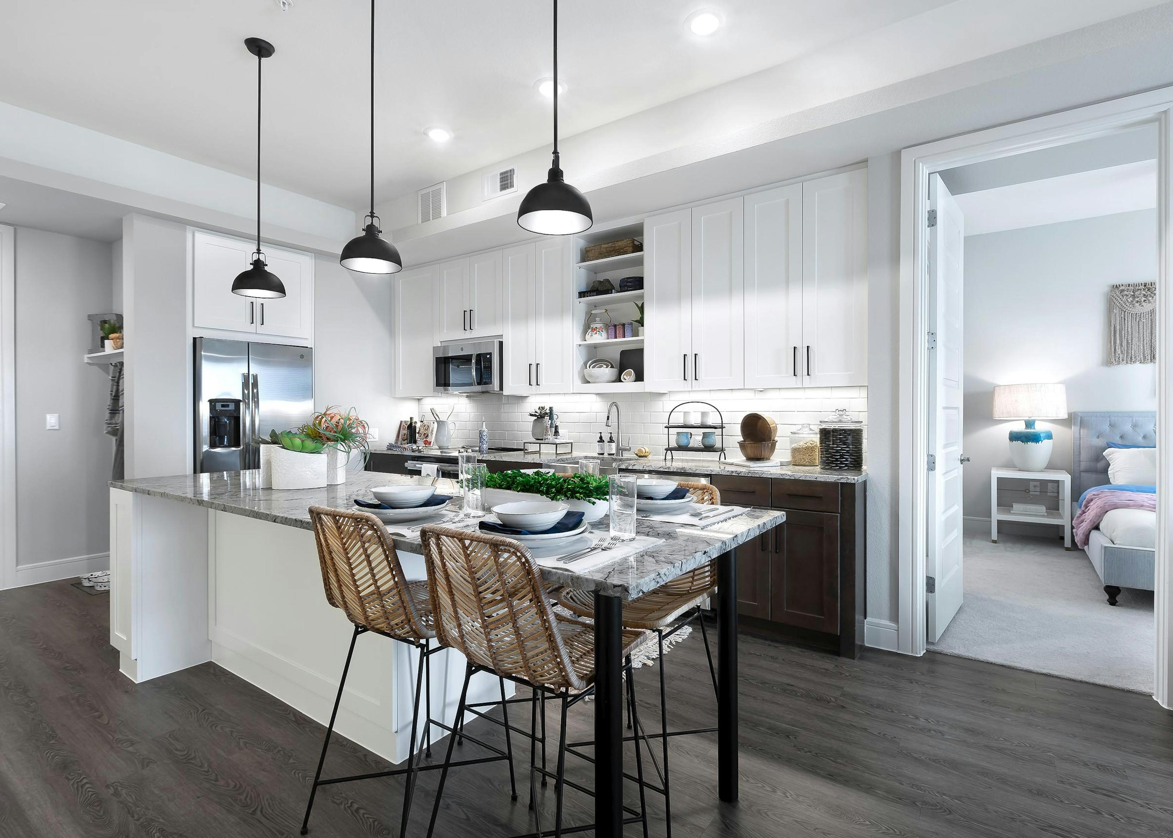 AMLI Lakeline apartment kitchen with stainless steel appliances and dining island with gray granite countertops