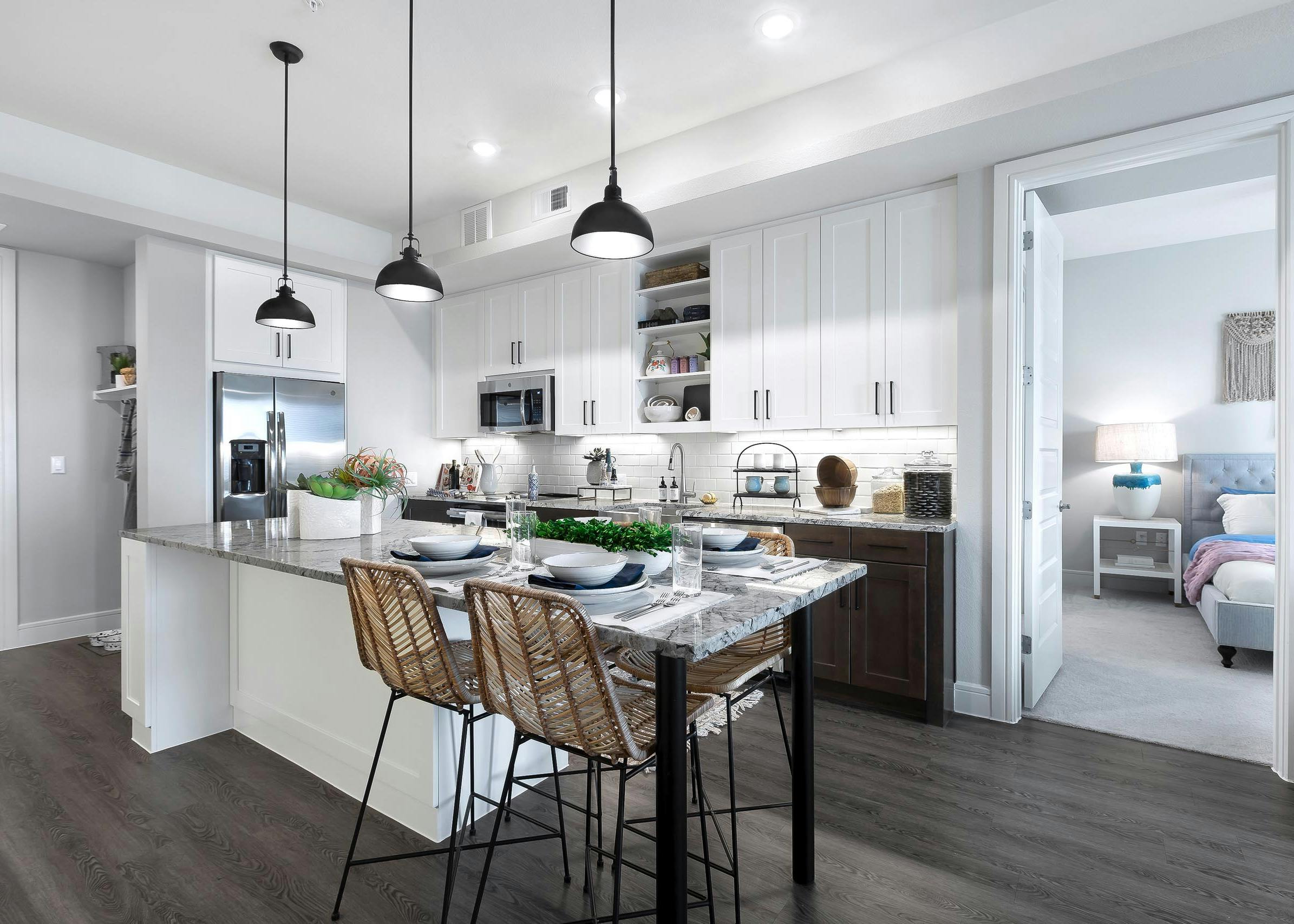 AMLI Lakeline apartment kitchen with stainless steel appliances and dining island with gray granite countertops