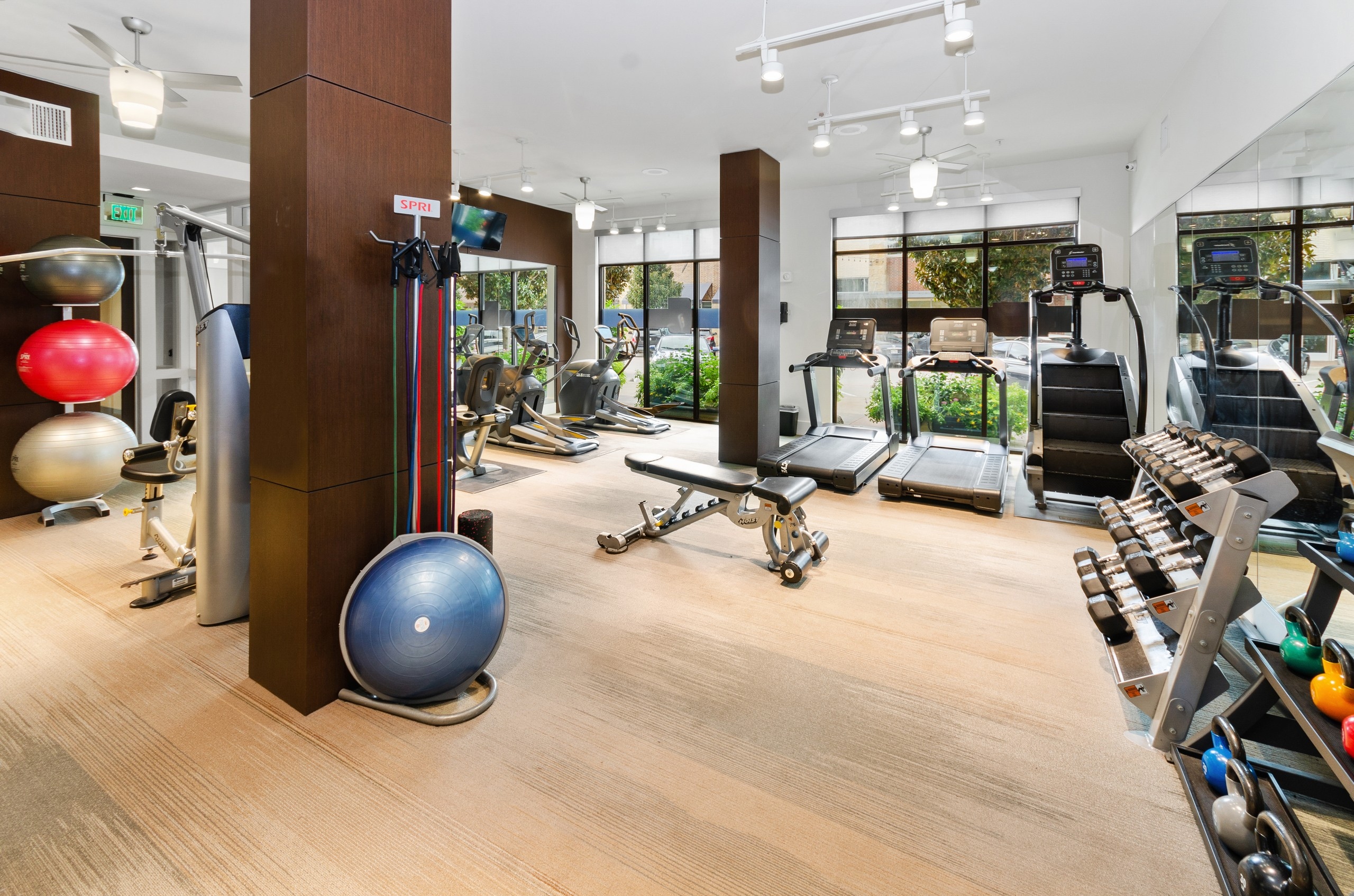 AMLI West Plano fitness center with a standalone weight station and a variety of cardio machines facing the outside street
