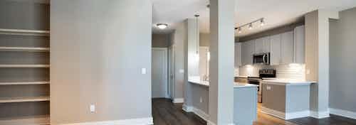 Interior close up of built in wall shelving at AMLI Eastside with dark floors and grey walls with kitchen in background