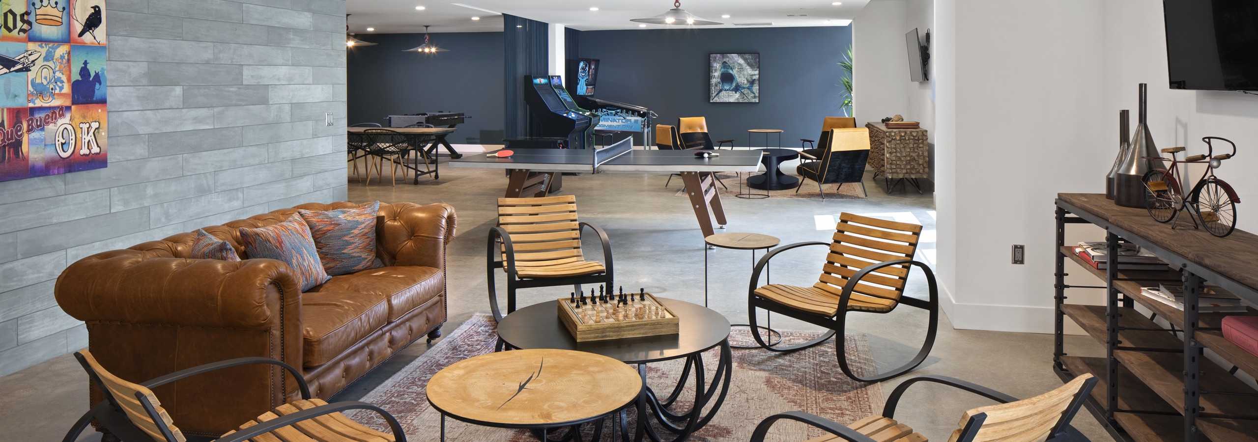 Interior daytime view of AMLI Marina De Rey apartment game lounge with arcade machines, tables and seating and big screen TVs