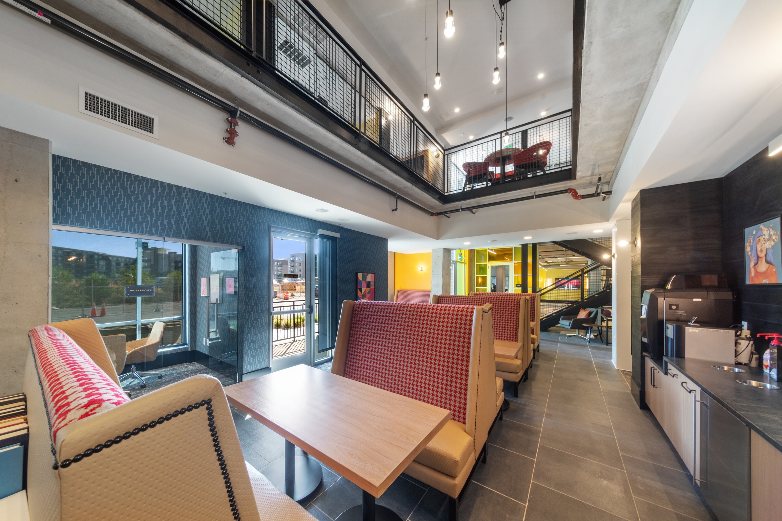 2 story coworking space at AMLI RiNo with booth seating and counter with coffee machine and glass enclosed private work space