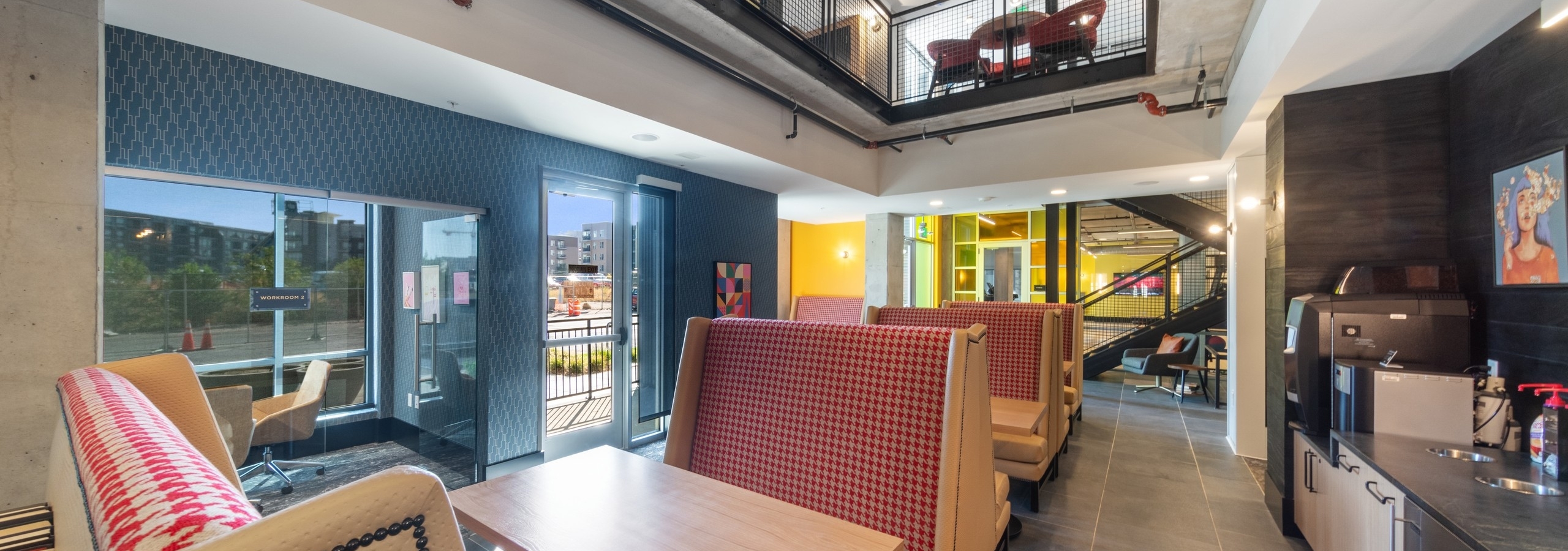 2 story coworking space at AMLI RiNo with booth seating and counter with coffee machine and glass enclosed private work space