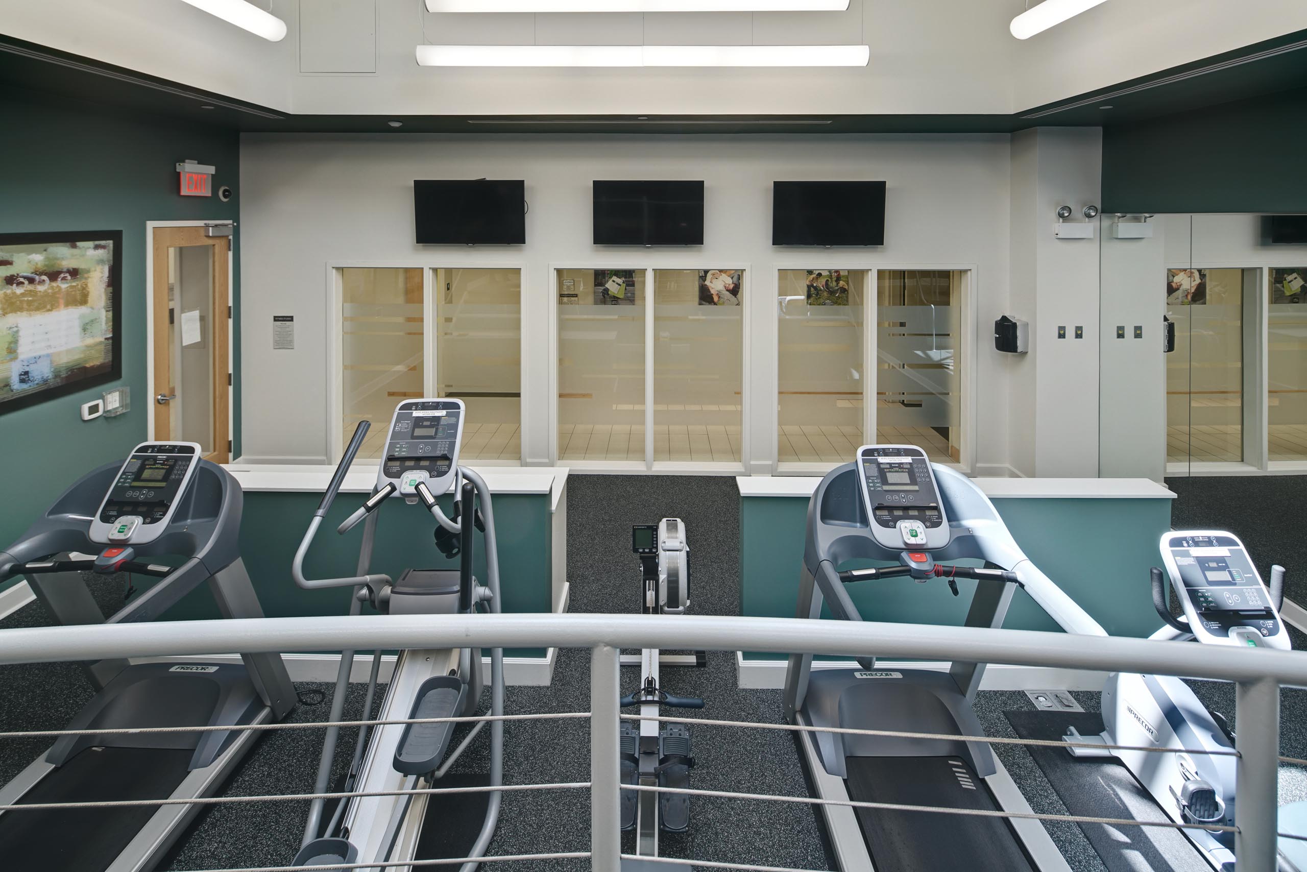 Exercise machines in fitness center facing windows showing a view of AMLI Evanston apartment community common area space