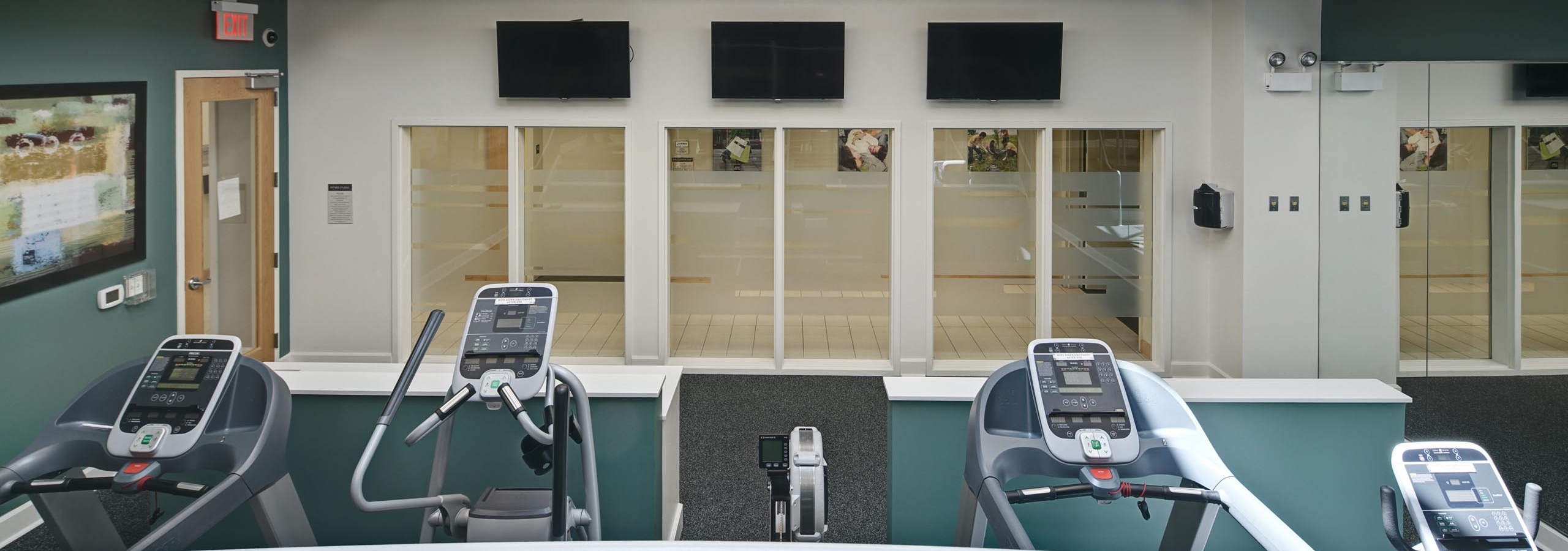 Exercise machines in fitness center facing windows showing a view of AMLI Evanston apartment community common area space
