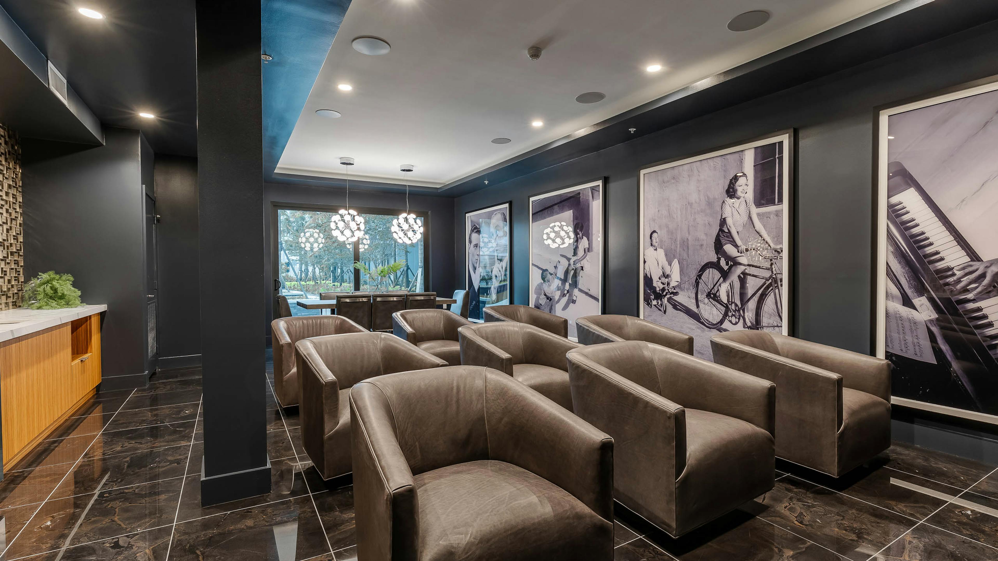The media theatre at AMLI Park West apartments with leather armchairs and large black and white wall photos and chandeliers  
