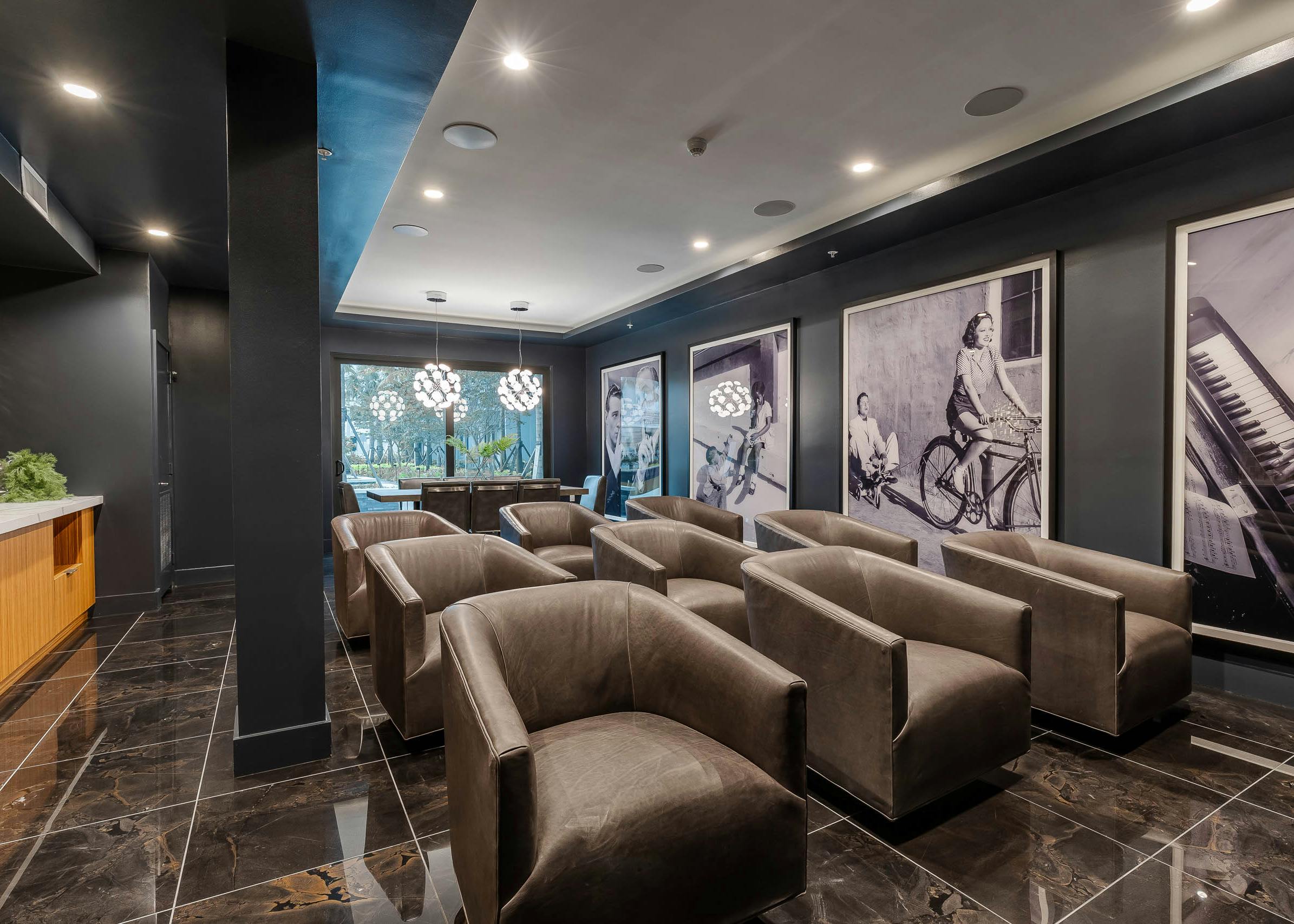 The media theatre at AMLI Park West apartments with leather armchairs and large black and white wall photos and chandeliers