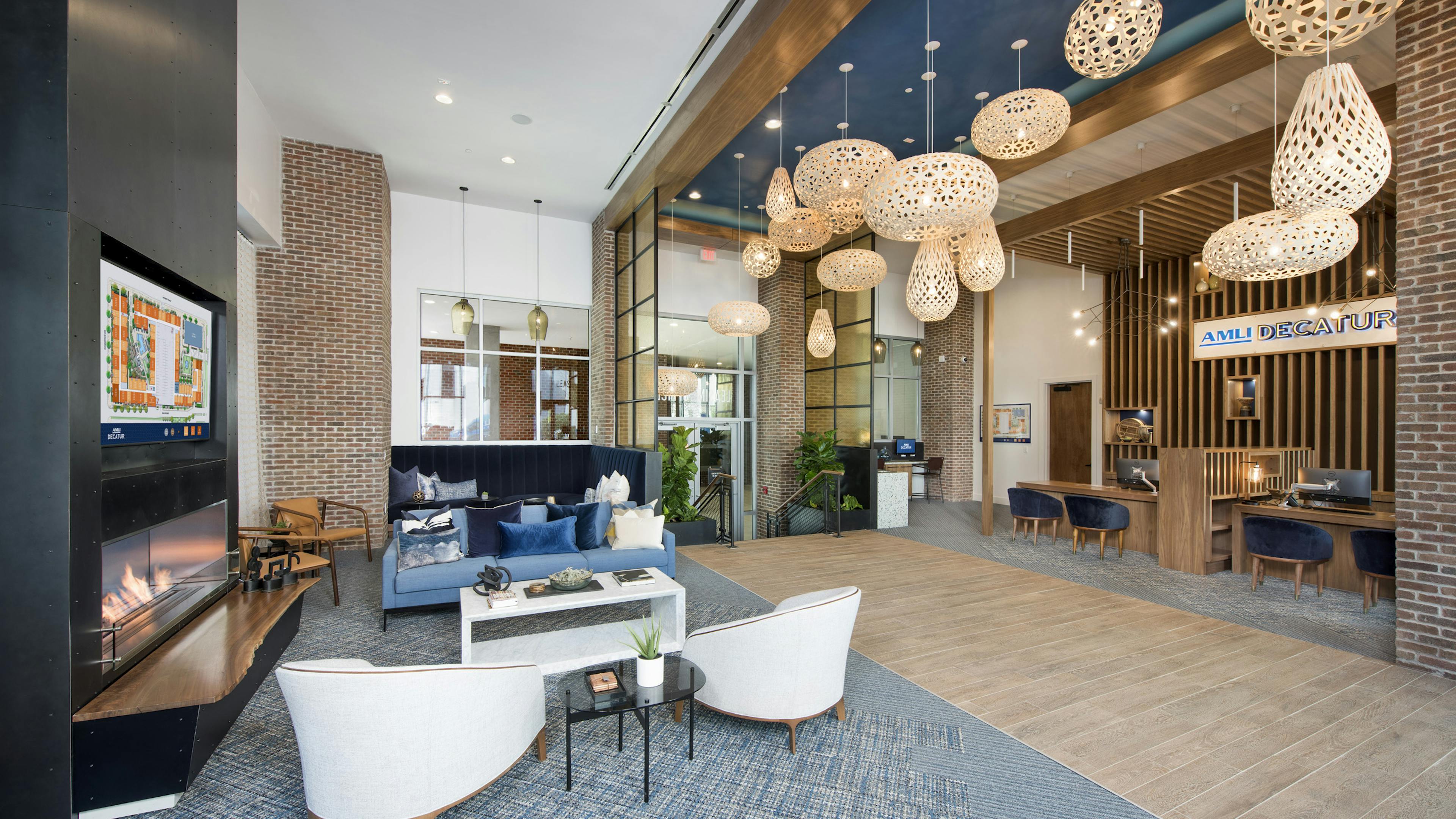 Interior leasing office at AMLI Decatur with fireplace, comfortable seating, floating decorative light fixtures and leasing desks