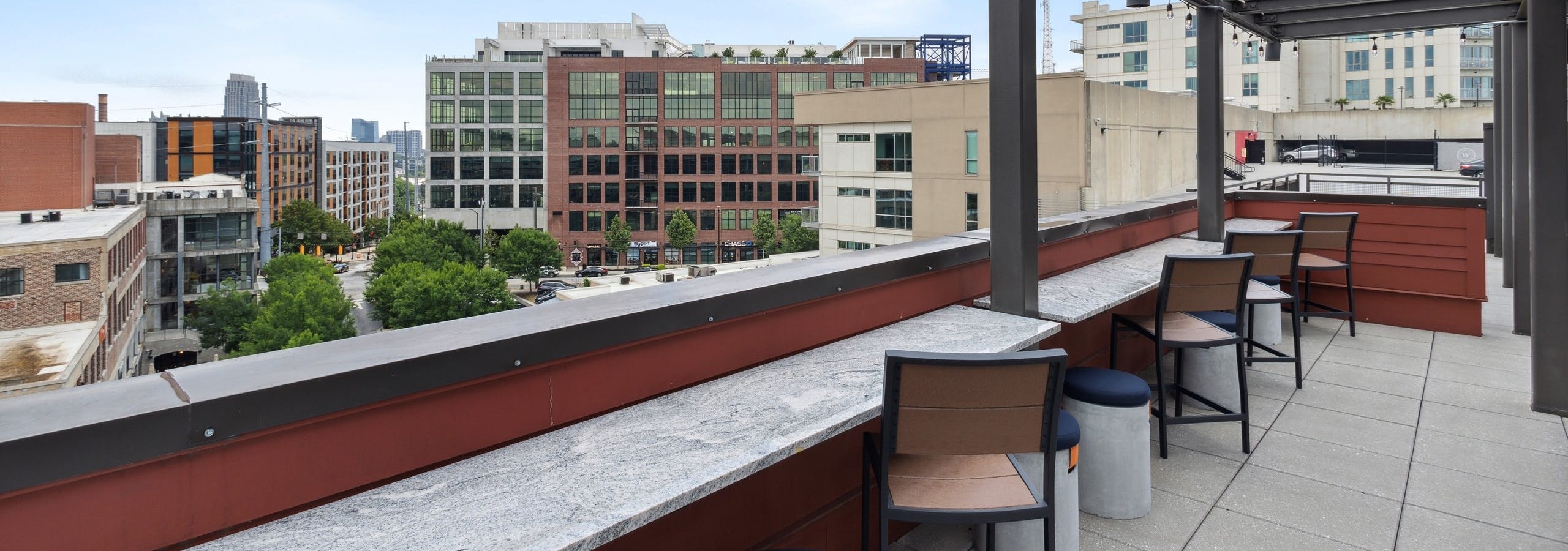 Rooftop lounge side bar with hanging lights and wooden chairs with Midtown skyline views at AMLI Westside apartments