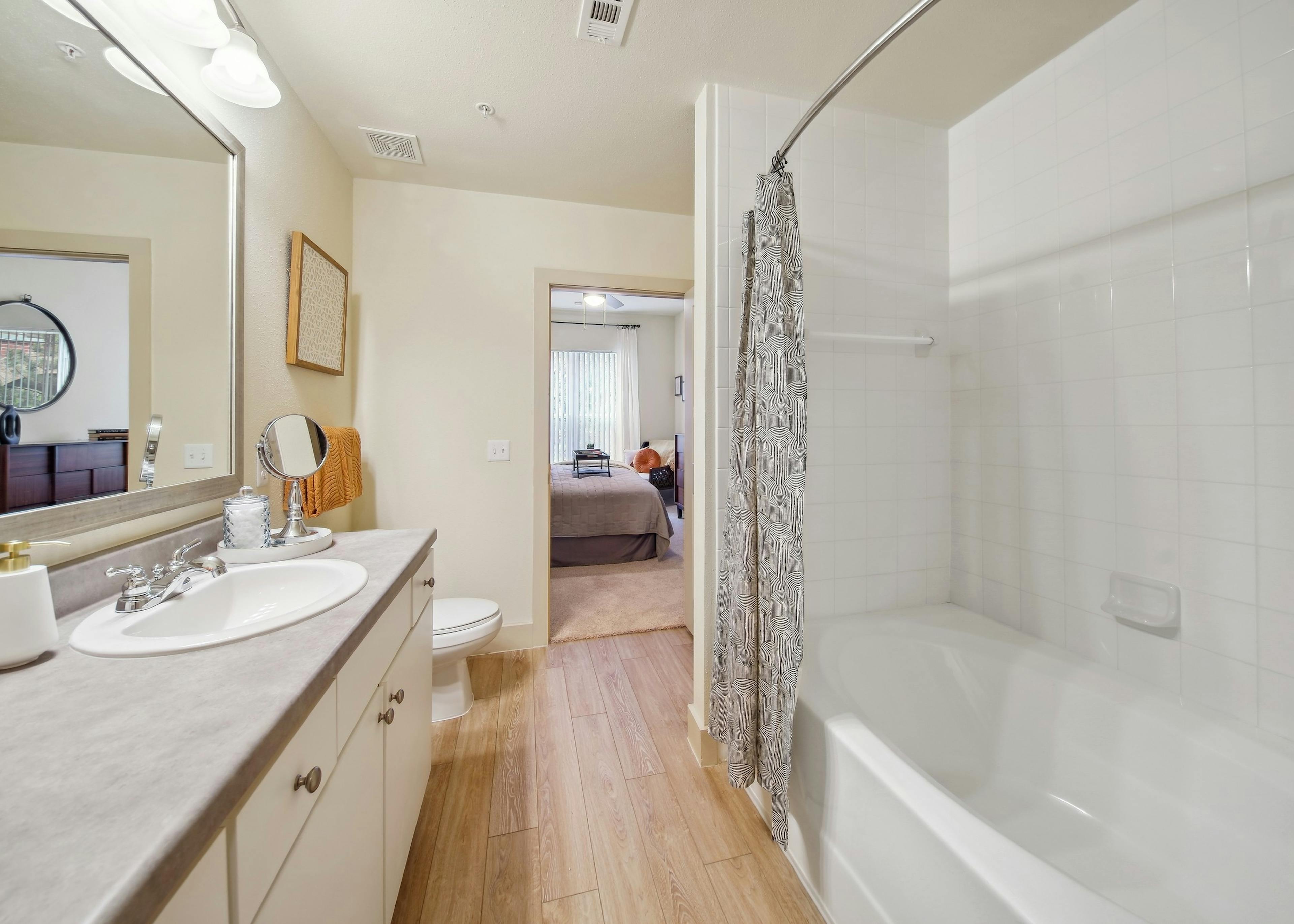 AMLI Park Avenue bathroom showcasing a garden tub and sink with a large vanity countertop space and a view into a bedroom