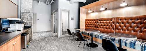 Coworking space at AMLI Spring District apartments with private offices and brown booth with tables and computer and printer
