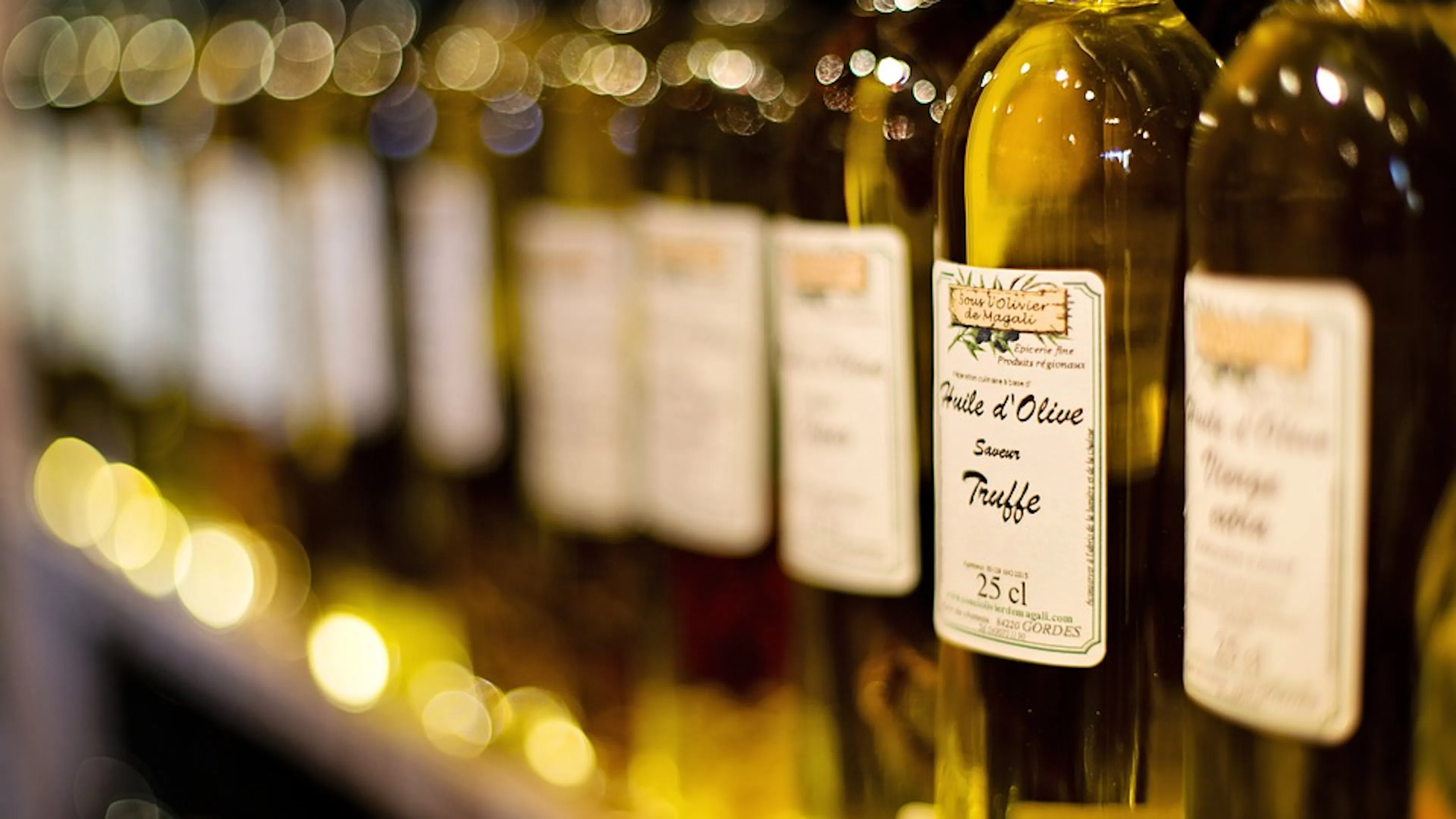 A row of tall oil jars filled with truffle olive oil shining in the light