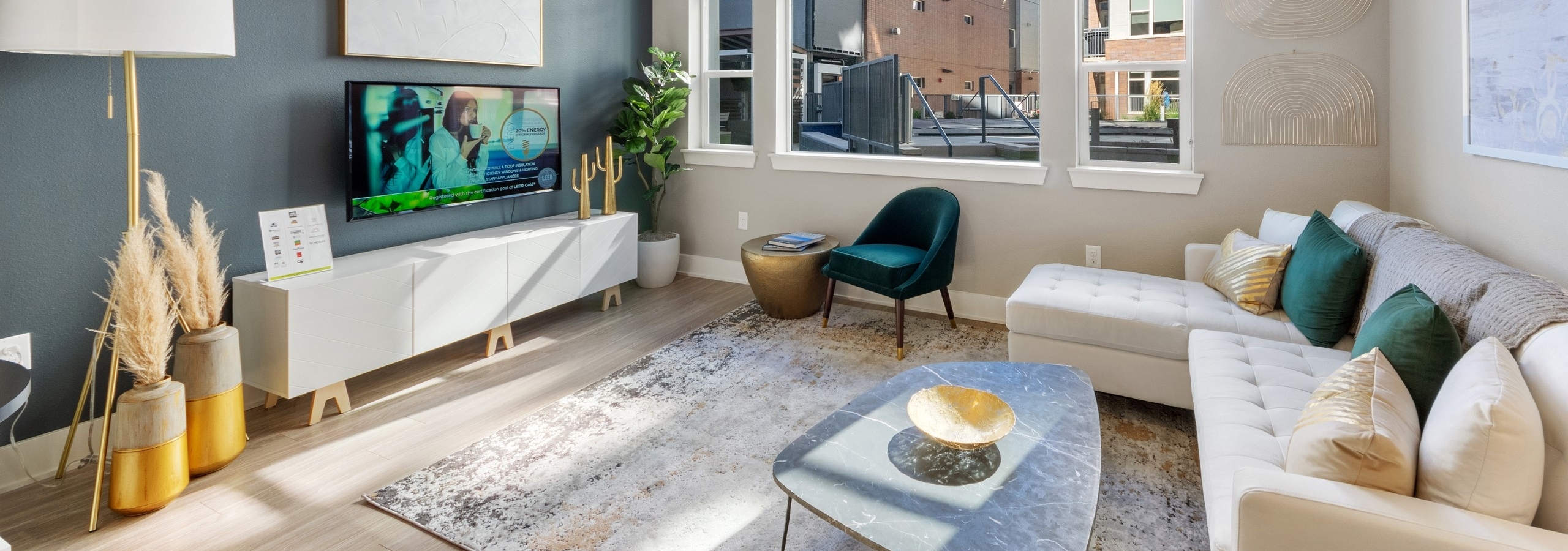 Apartment living room at AMLI Riverfront Green featuring a teal accent wall and bright window paired with neutral furnishings