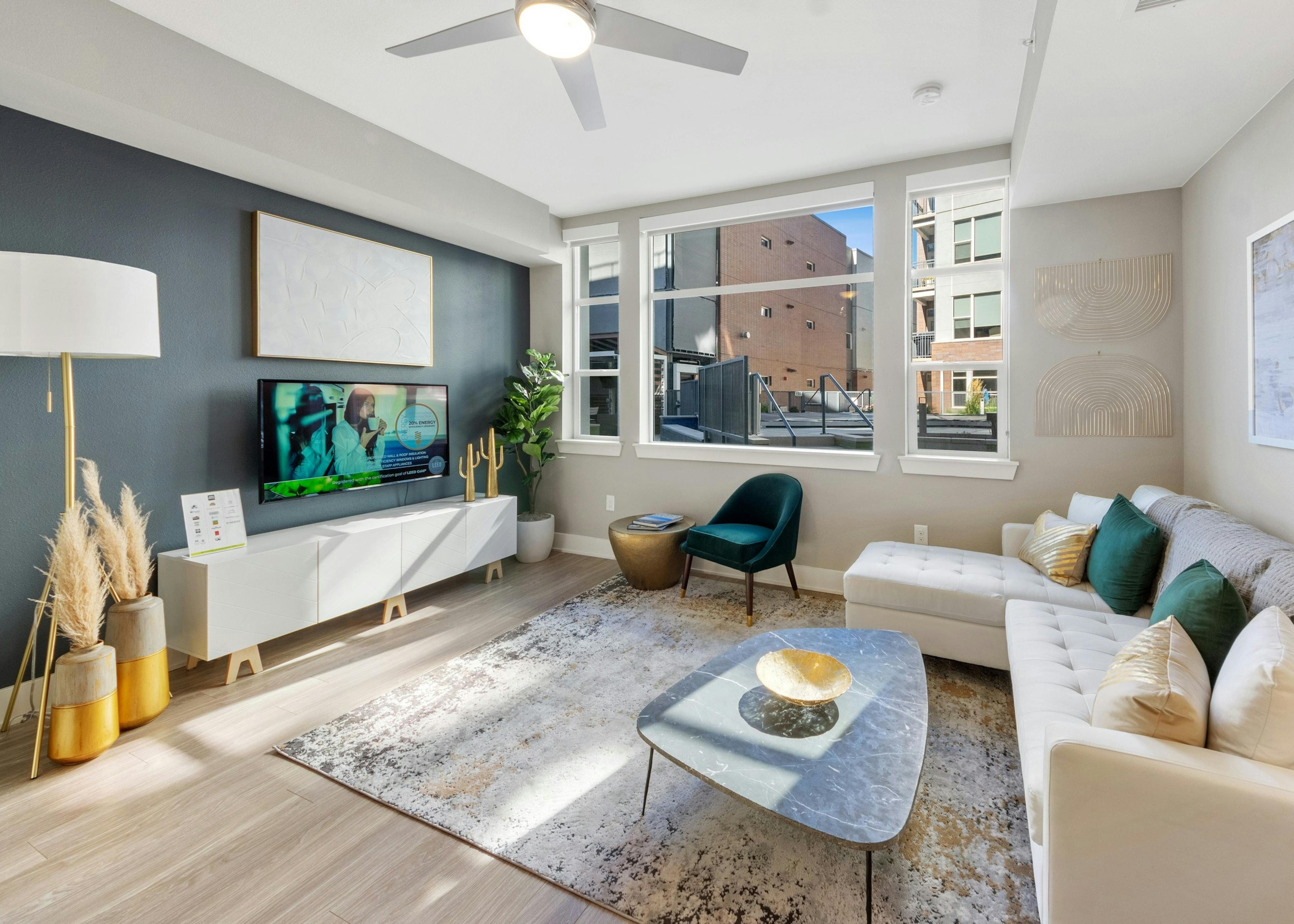 Apartment living room at AMLI Riverfront Green featuring a teal accent wall and bright window paired with neutral furnishings