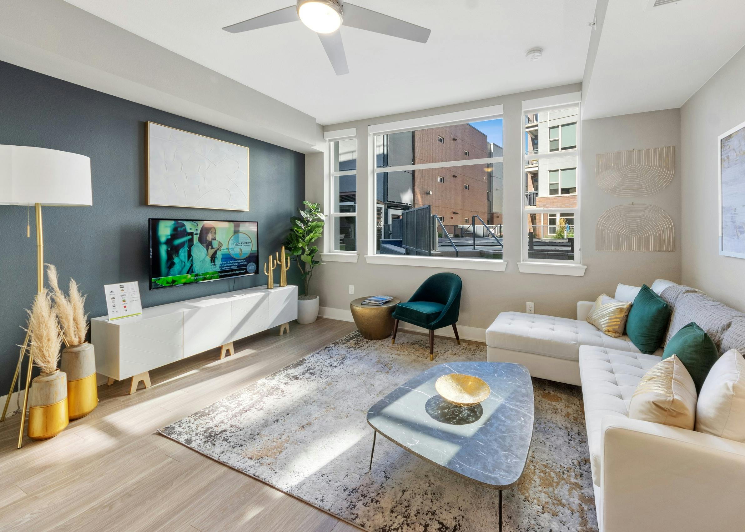 Apartment living room at AMLI Riverfront Green featuring a teal accent wall and bright window paired with neutral furnishings