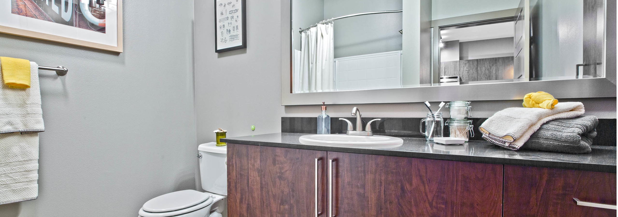Interior view of an AMLI Mark24 apartment bathroom with grey walls and lots of dark cabinet storage