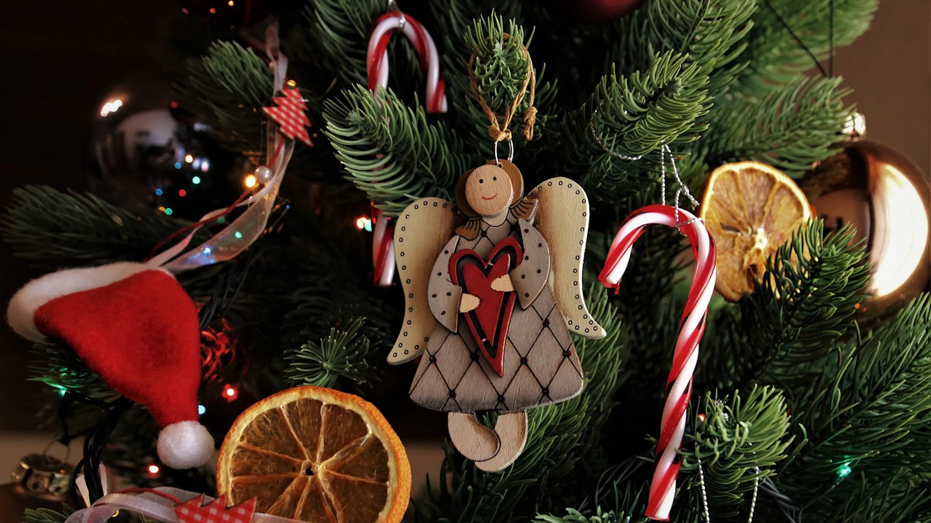 A wooden angel ornament on a festive Christmas tree