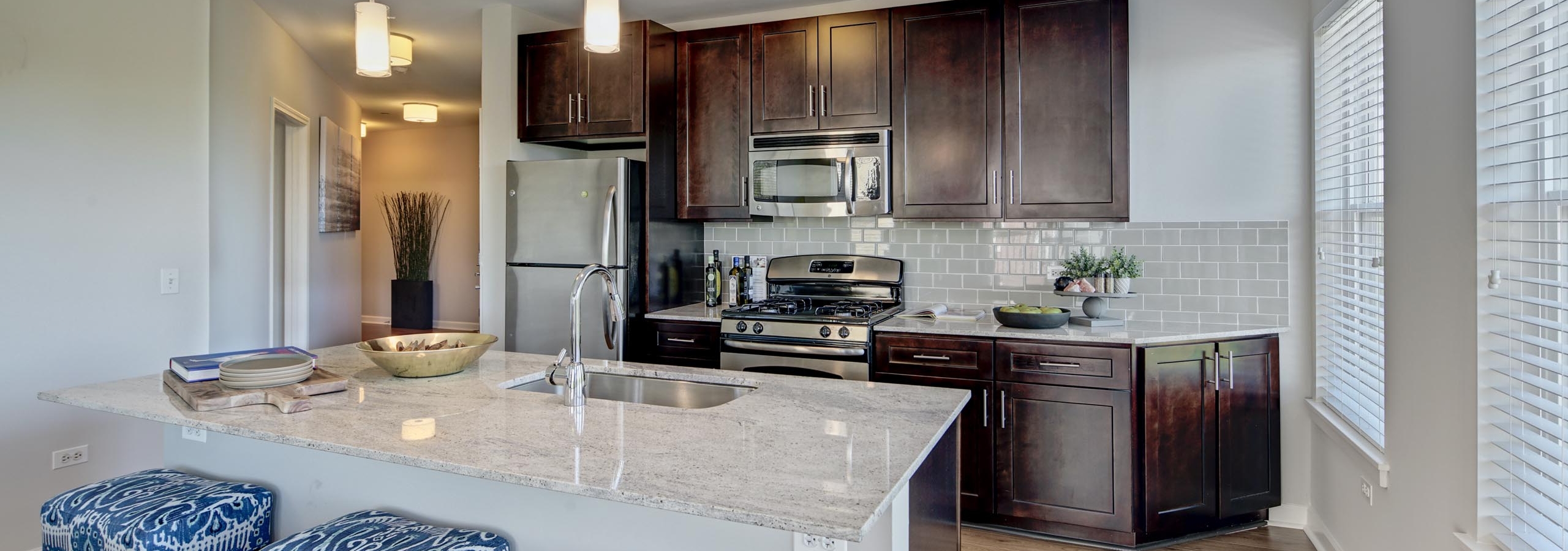 Vibrant patterned barstools in an AMLI Evanston apartment kitchen with view of dark cabinetry and stainless steel appliances