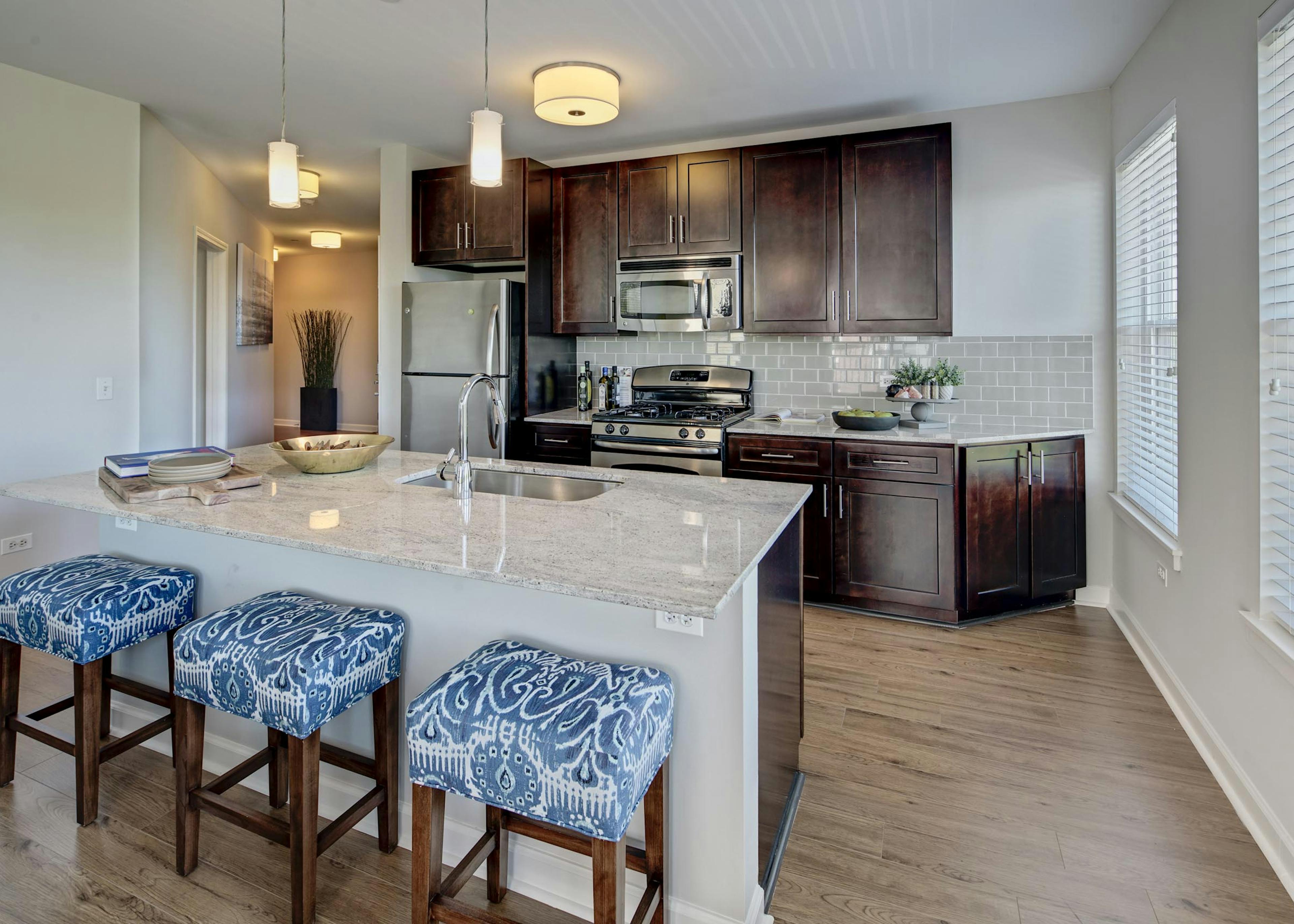 Vibrant patterned barstools in an AMLI Evanston apartment kitchen with view of dark cabinetry and stainless steel appliances 