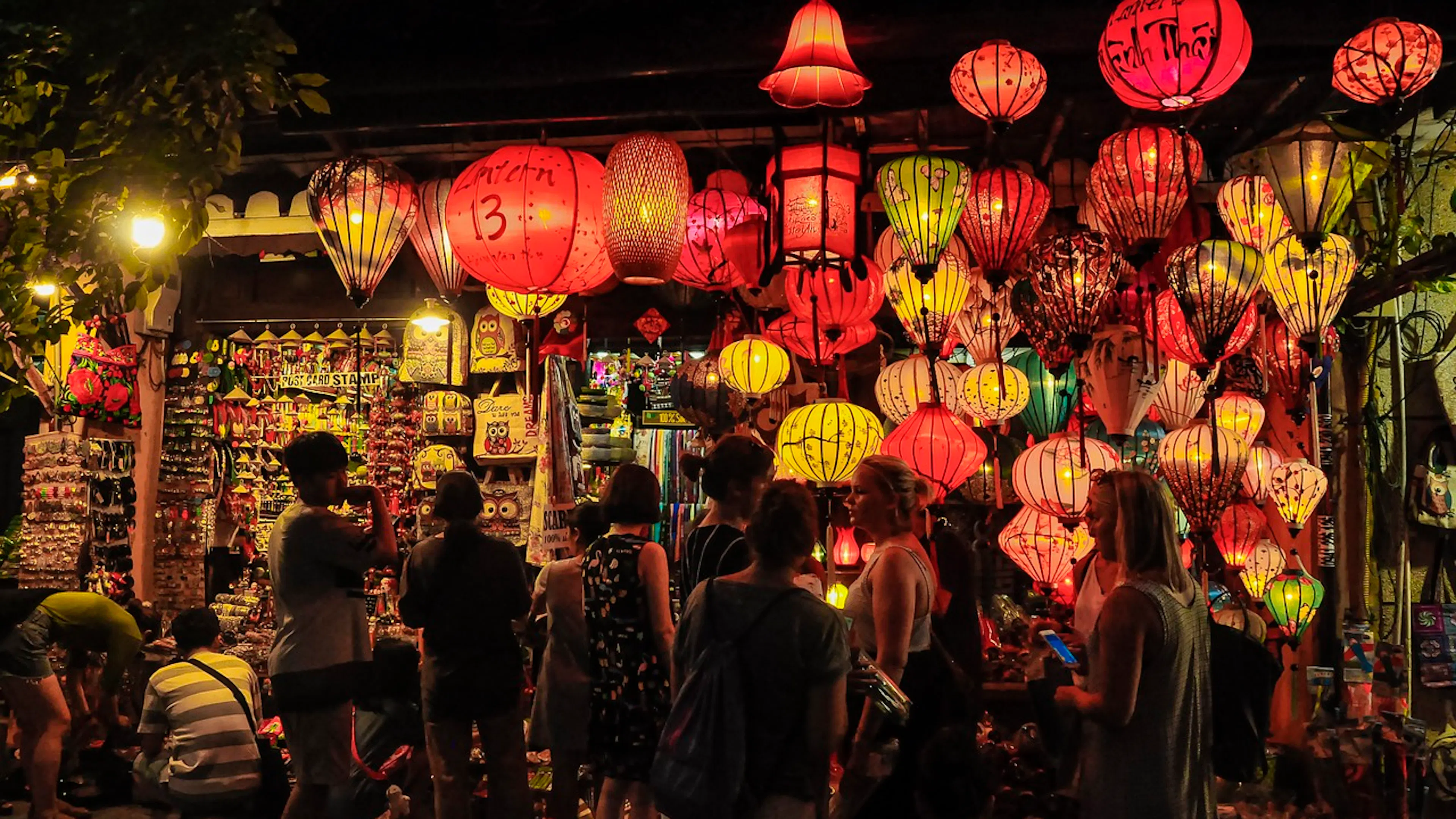 A street shop at night with red lanterns hung all over the roof and walkways