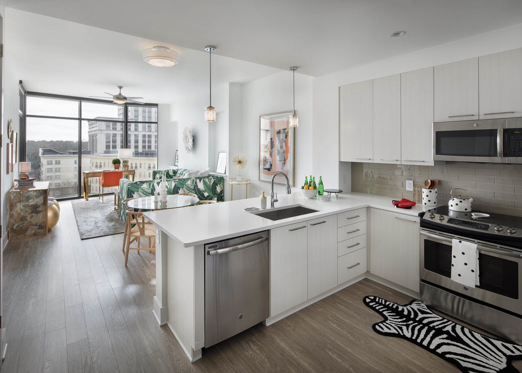 AMLI 3464 kitchen with white cabinets and countertops and view of the living room with floor to ceiling windows