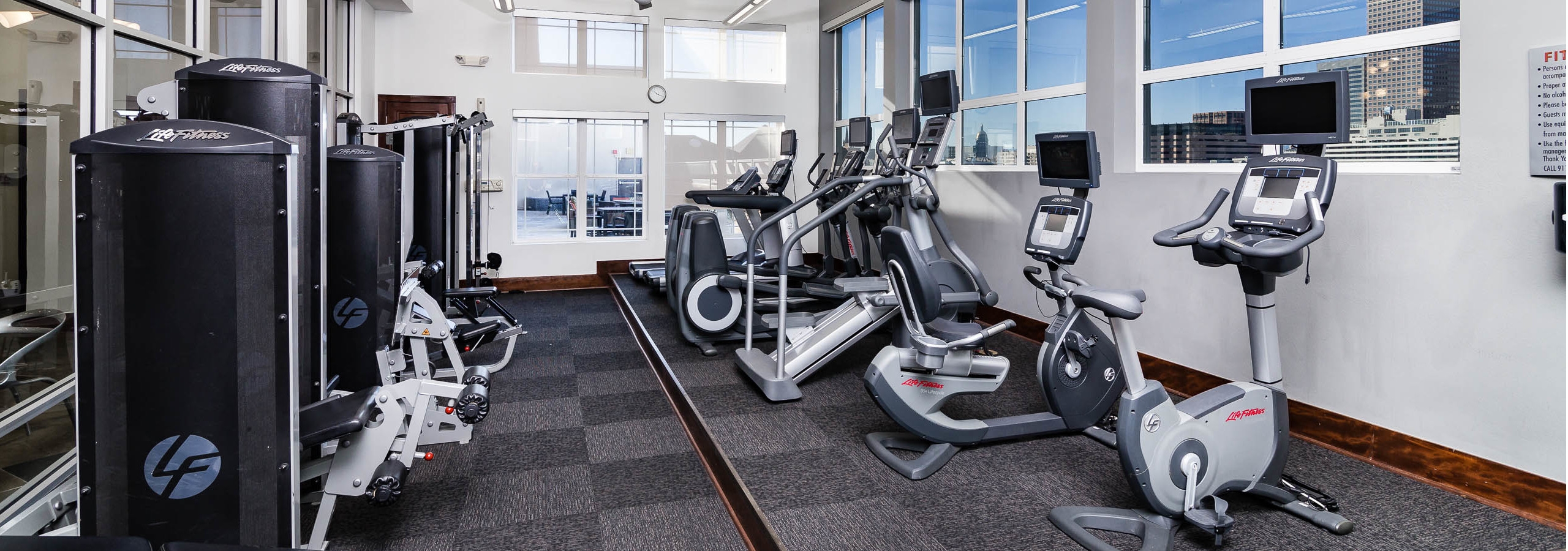Interior of the fitness center at AMLI Park Avenue apartments with treadmills and elliptical training machines and windows