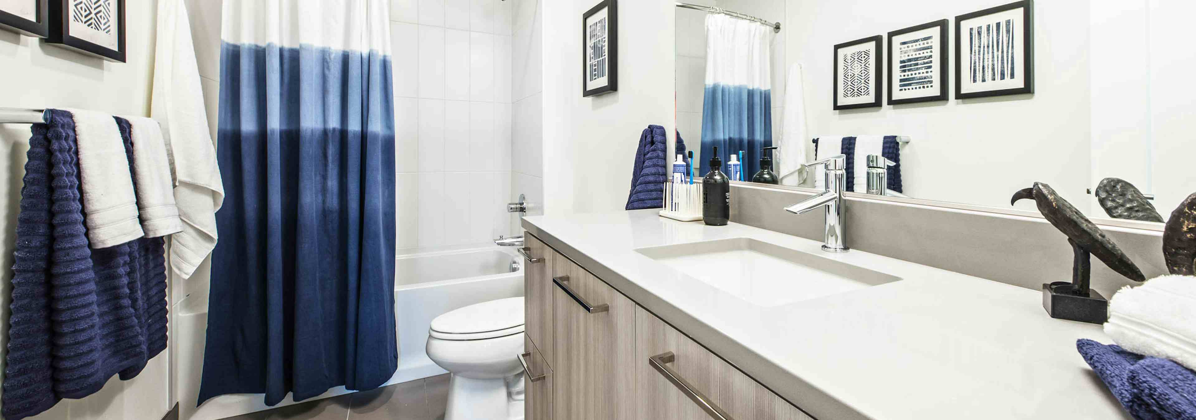 Interior view of AMLI Arc apartment bathroom with toilet shower and tub combination with white quartz counter tops