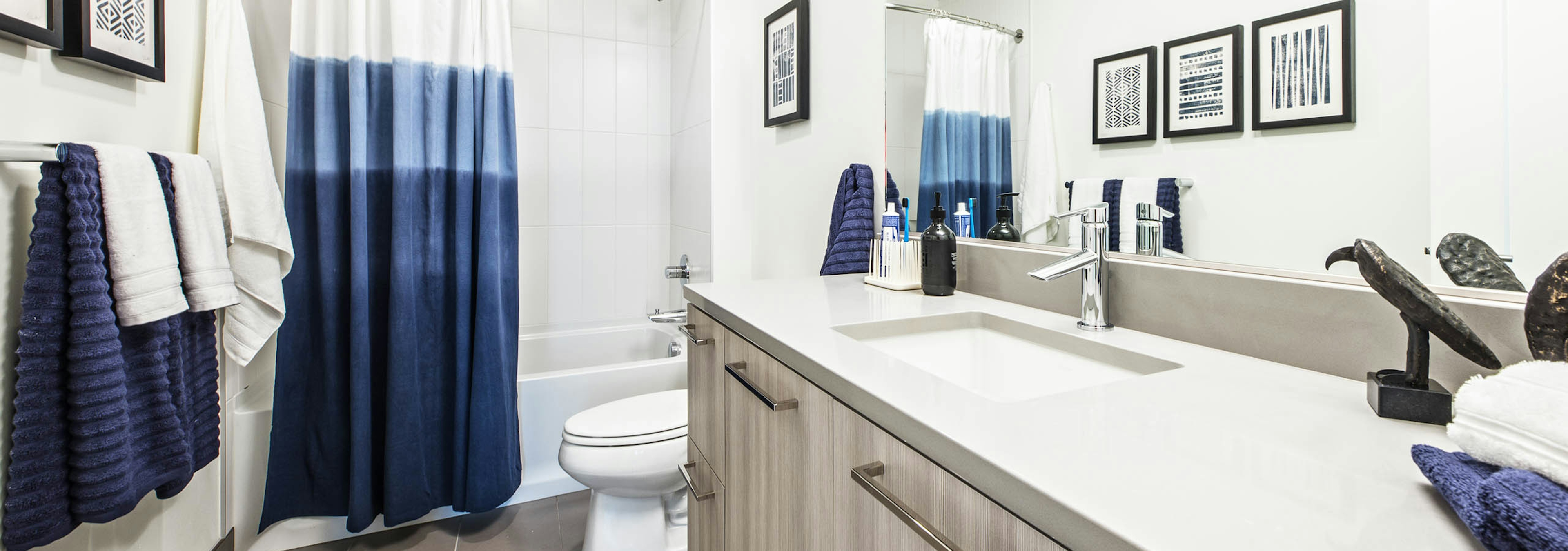 Interior view of AMLI Arc apartment bathroom with toilet shower and tub combination with white quartz counter tops