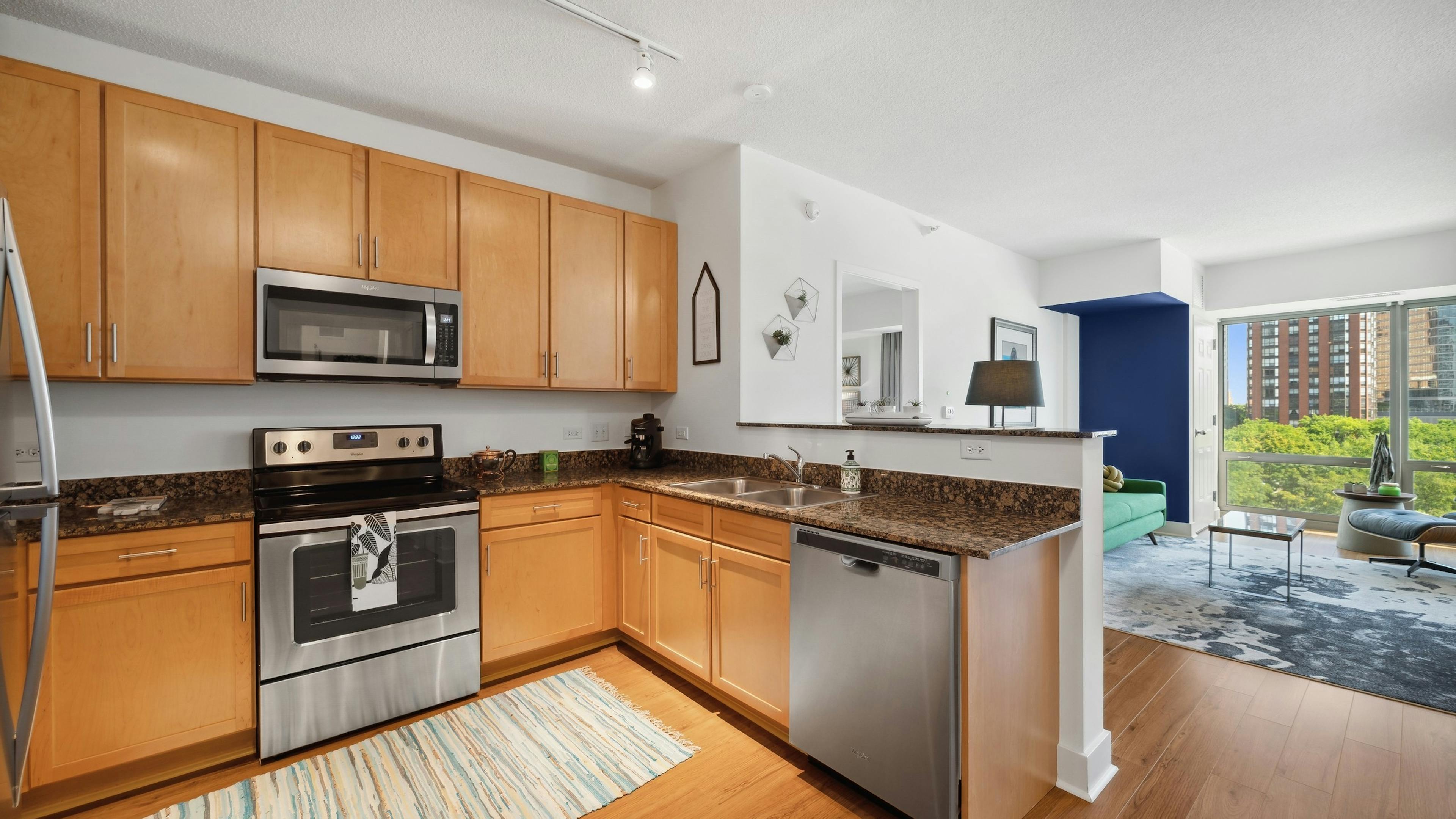 Spacious AMLI 900 apartment kitchen with maple cabinets and granite countertops paired with stainless appliances