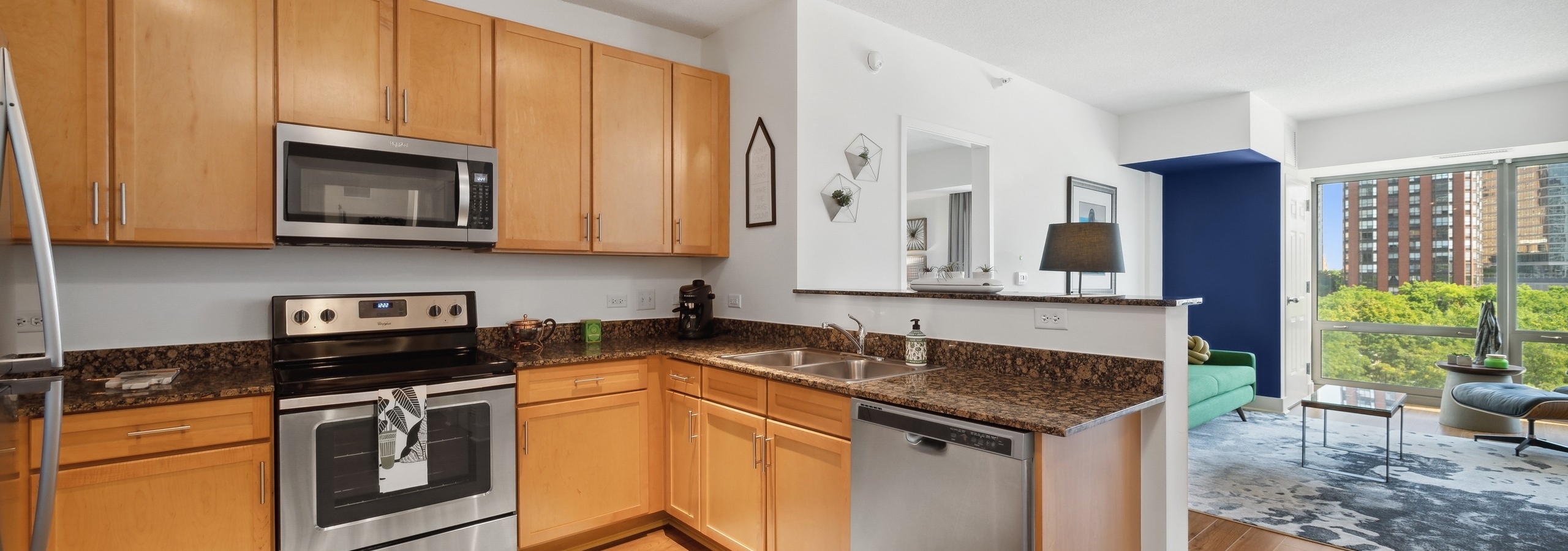Spacious AMLI 900 apartment kitchen with maple cabinets and granite countertops paired with stainless appliances
