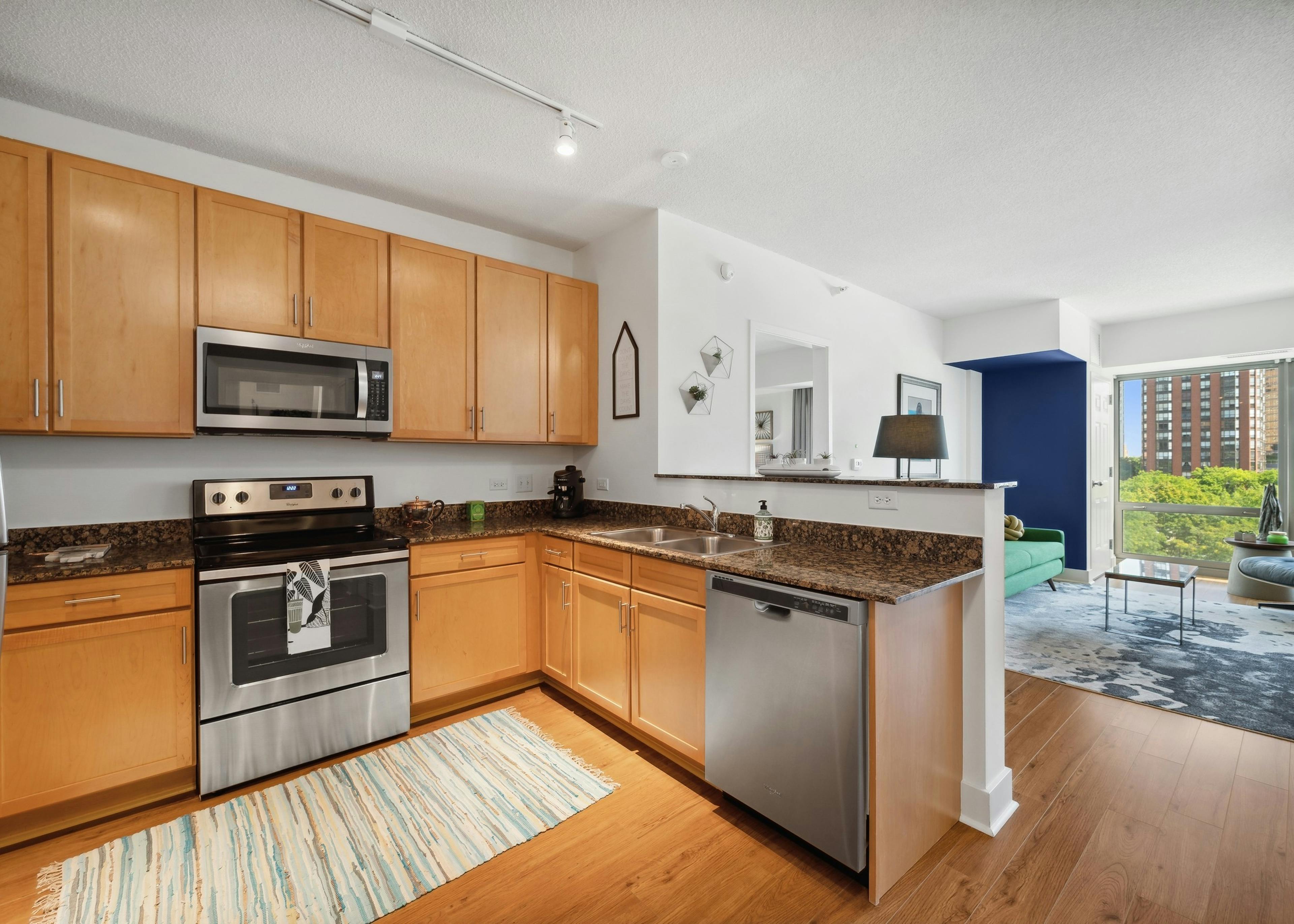 Spacious AMLI 900 apartment kitchen with maple cabinets and granite countertops paired with stainless appliances