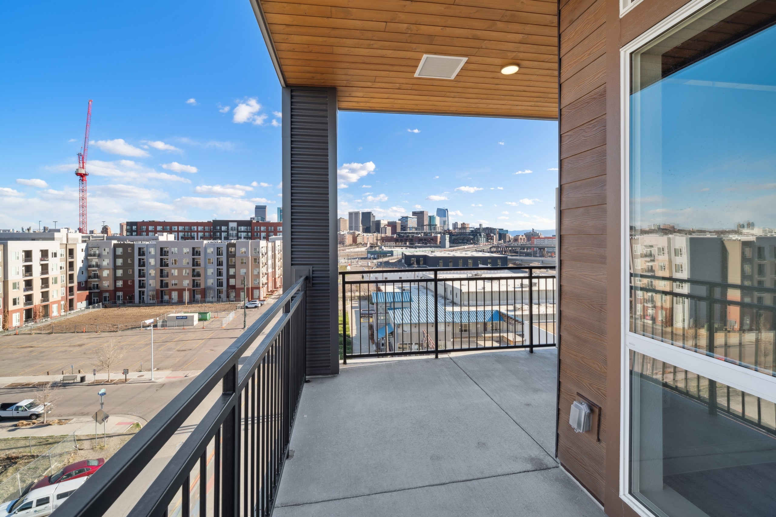 City and construction view from balcony at AMLI RiNo apartments with metal railing and wood siding and wood ceiling