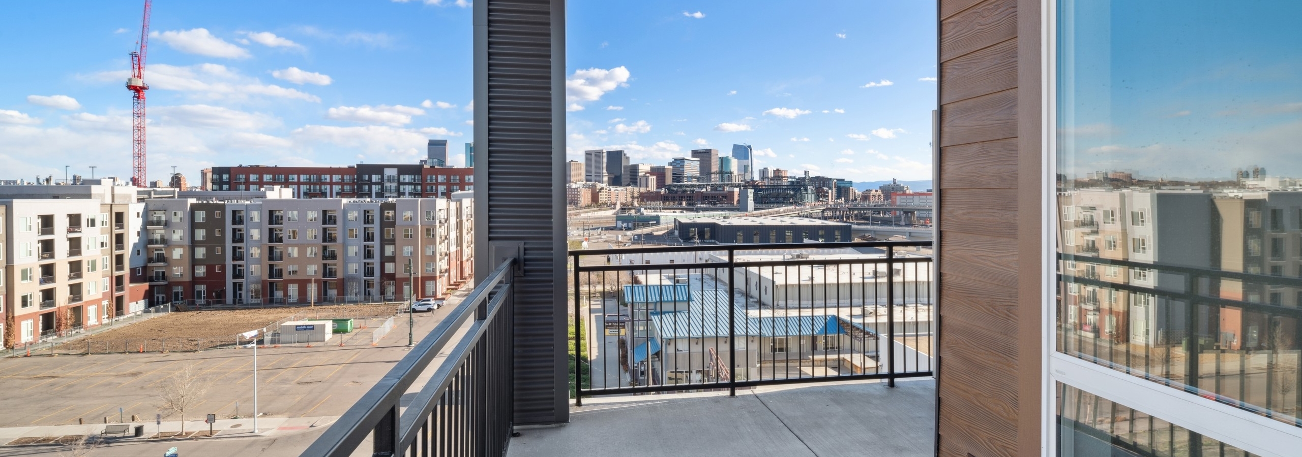 City and construction view from balcony at AMLI RiNo apartments with metal railing and wood siding and wood ceiling