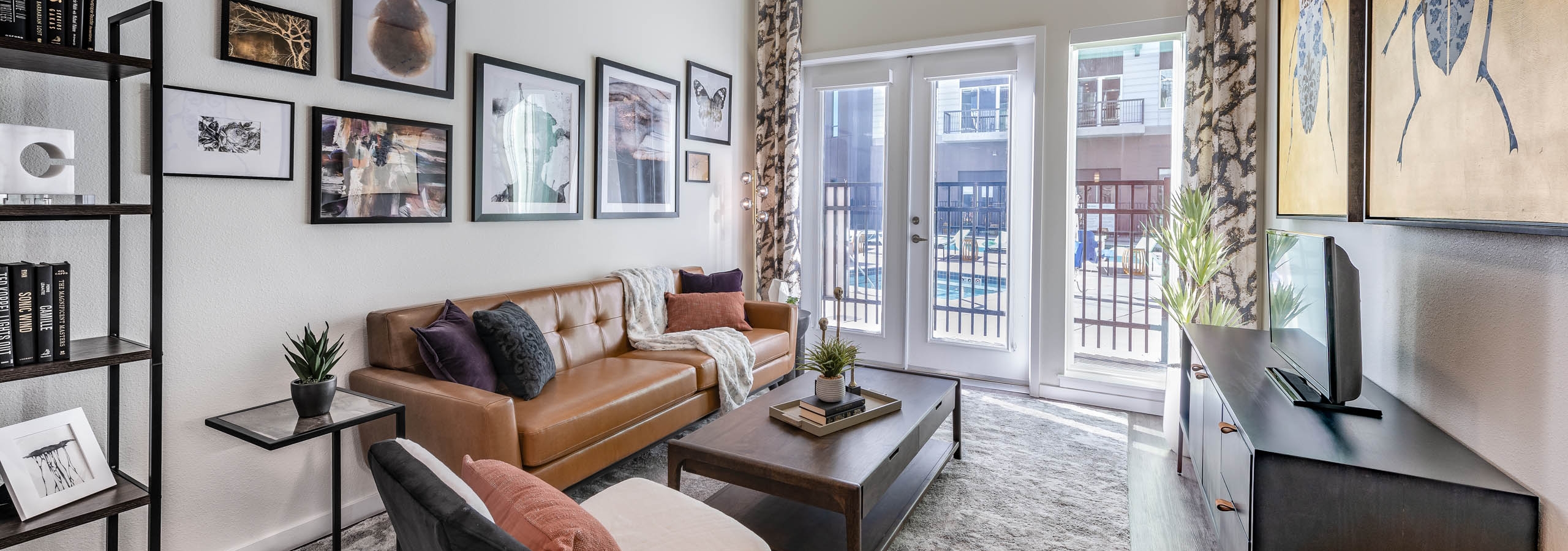AMLI Art District living room with a large area rug as well as a couch and chairs and a sunny view out to the swimming pool