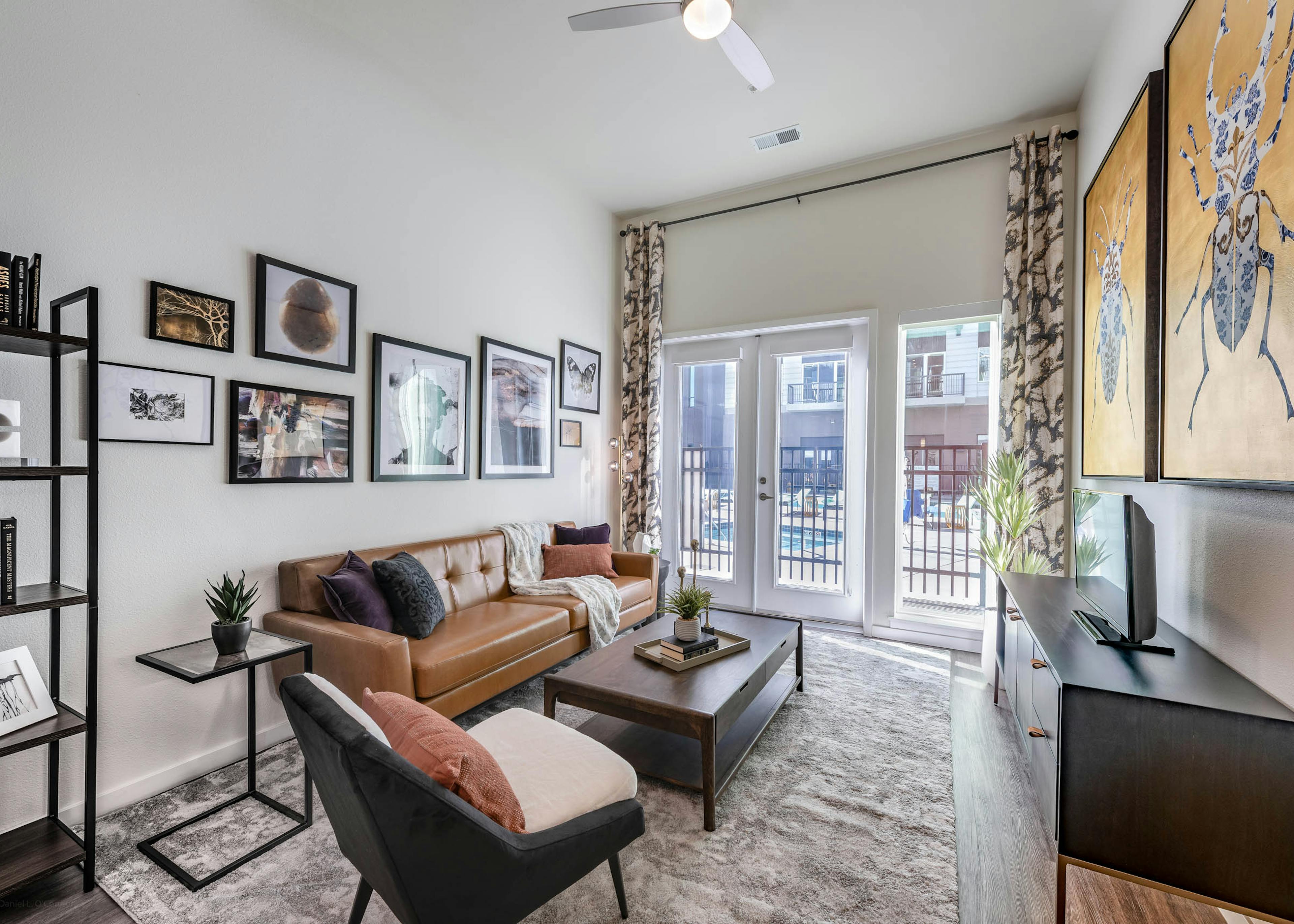 AMLI Art District living room with a large area rug as well as a couch and chairs and a sunny view out to the swimming pool