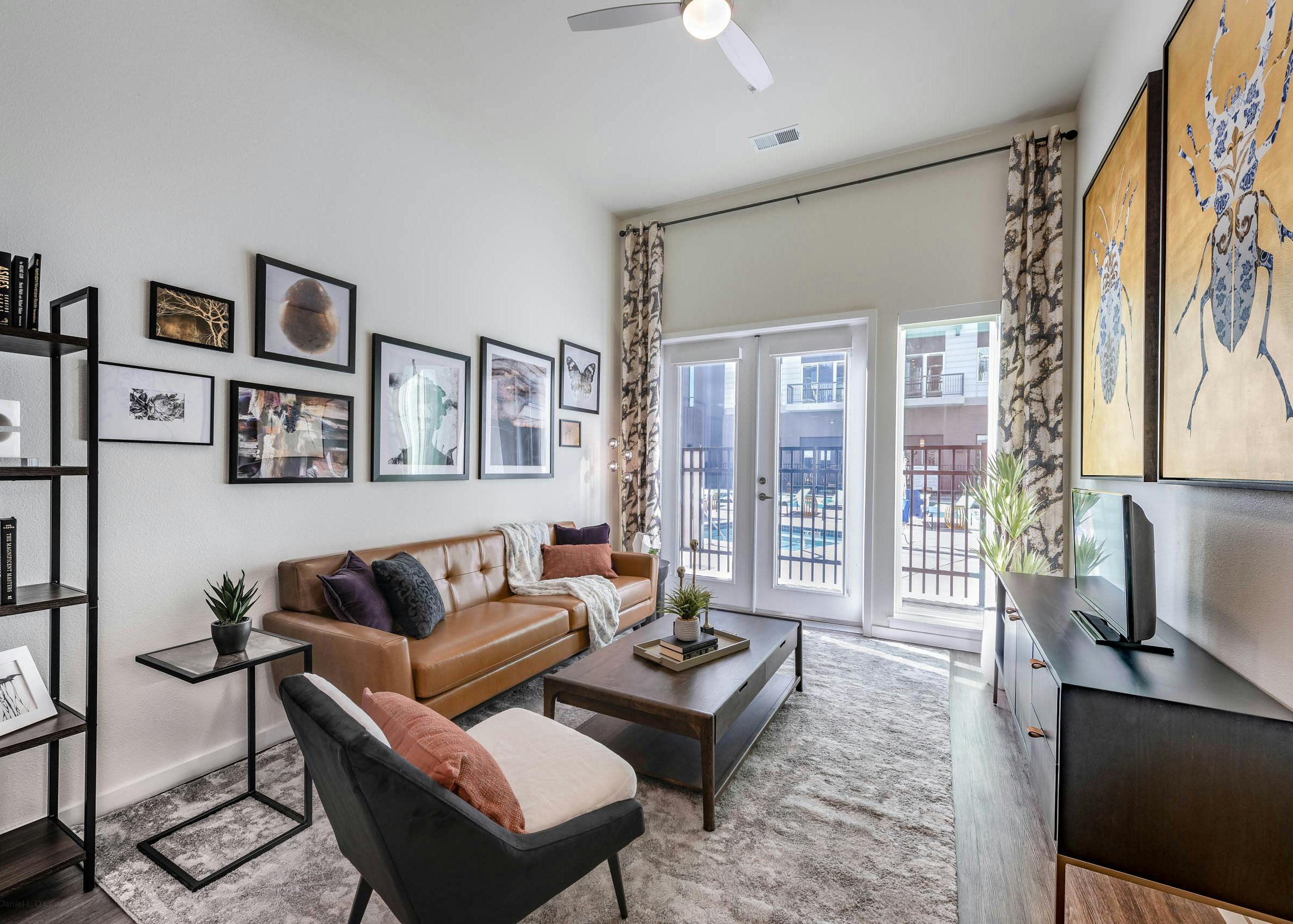 AMLI Art District living room with a large area rug as well as a couch and chairs and a sunny view out to the swimming pool